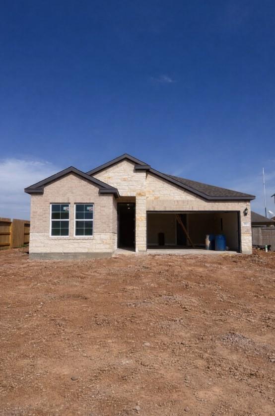 Modern beige brick single-story home with stone facade, open 2-car garage, and dirt yard in Sunterra, Katy, Texas - Davidson Homes Laguna C