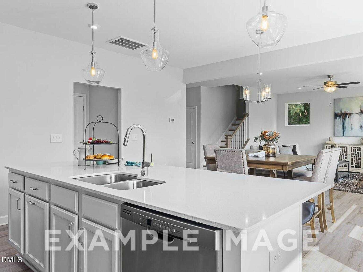 Modern open-concept kitchen with white quartz island, stainless sink, and dining nook in The Chestnut B floor plan, Lillington, NC