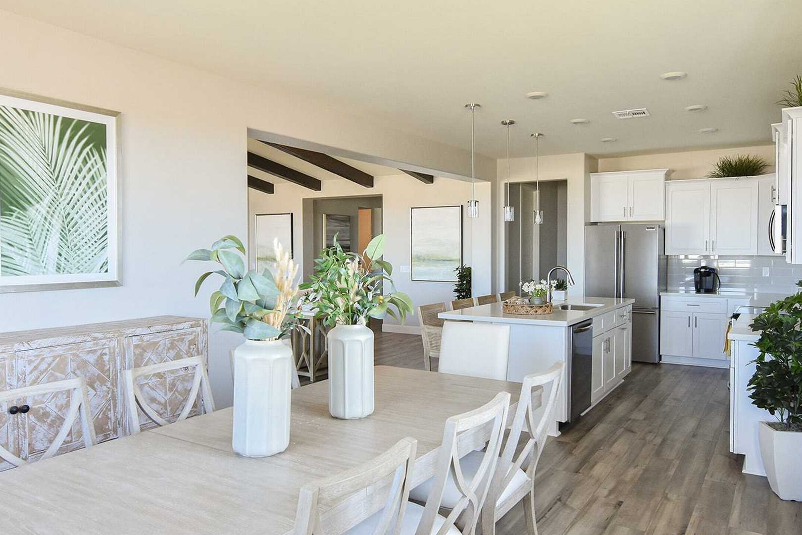 Spacious open-concept kitchen and dining in The Summit B by Evermore Homes, Prescott Valley, featuring white cabinets, wooden table, and potted plants