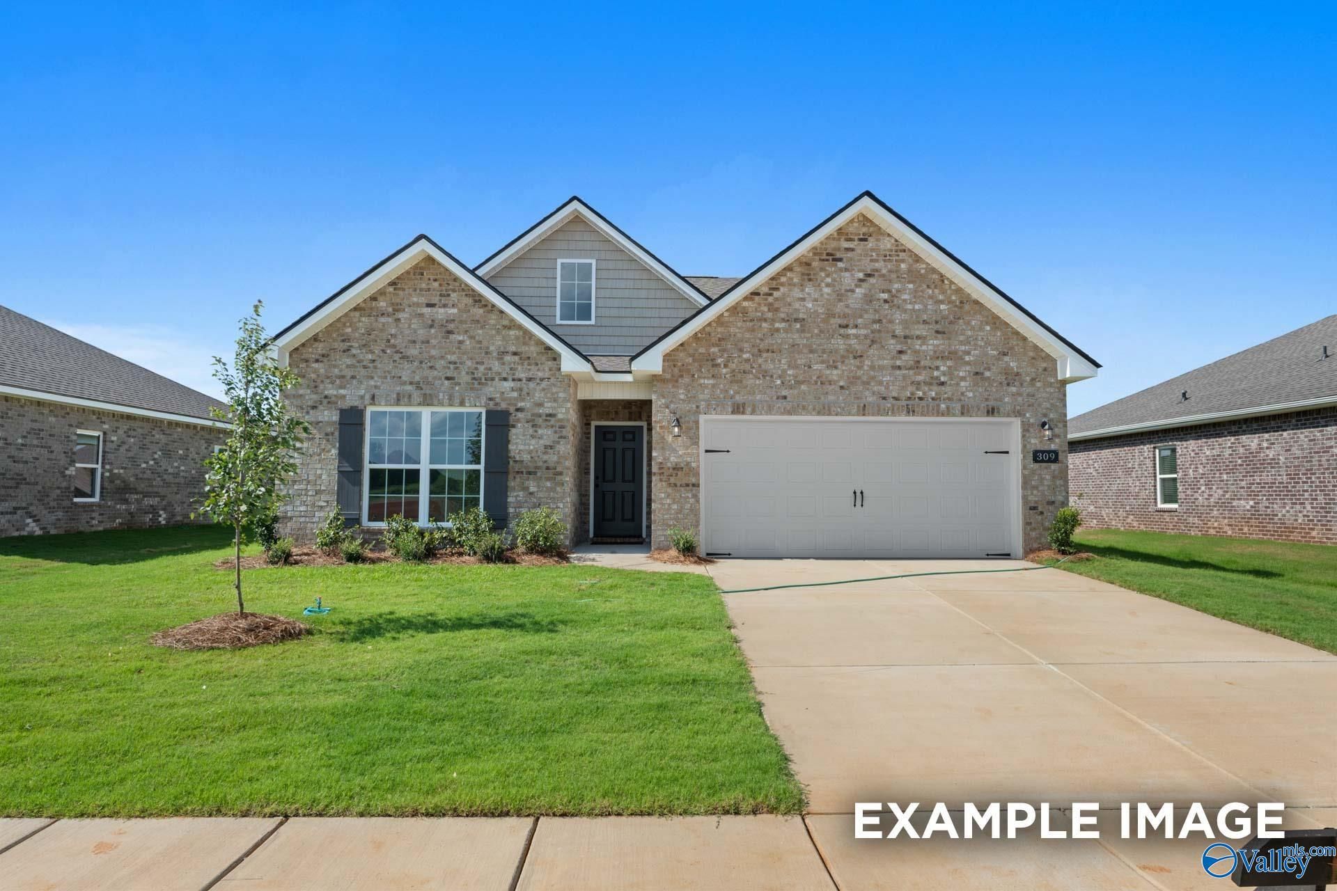 Single-story brick home with 2-car garage, driveway, lush green lawn, and young tree in Ramsay Cove, Owens Cross Roads, Alabama