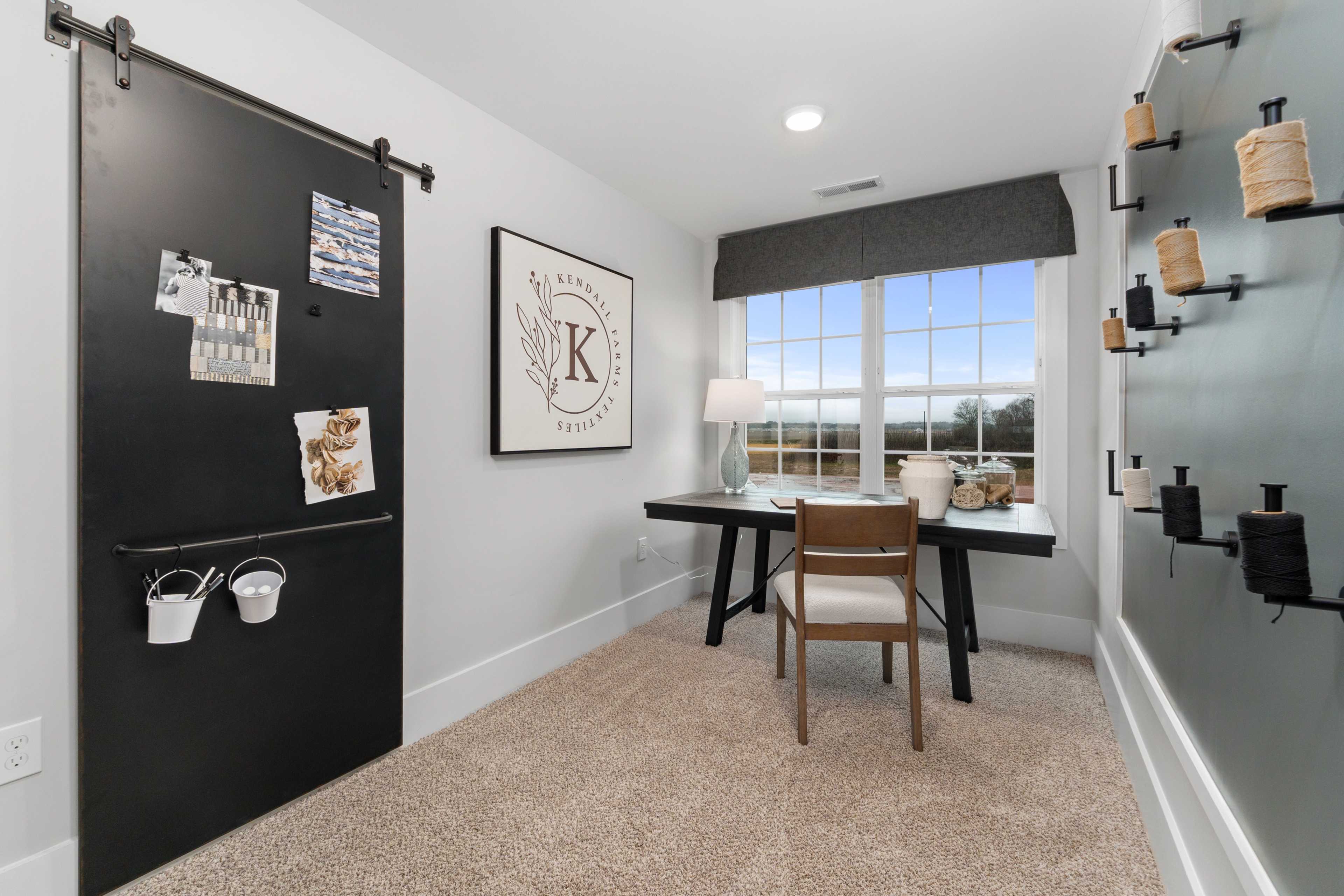 Cozy home office at Kendall Farms in Toney AL with sliding black barn door, wooden desk, chair, and large window view