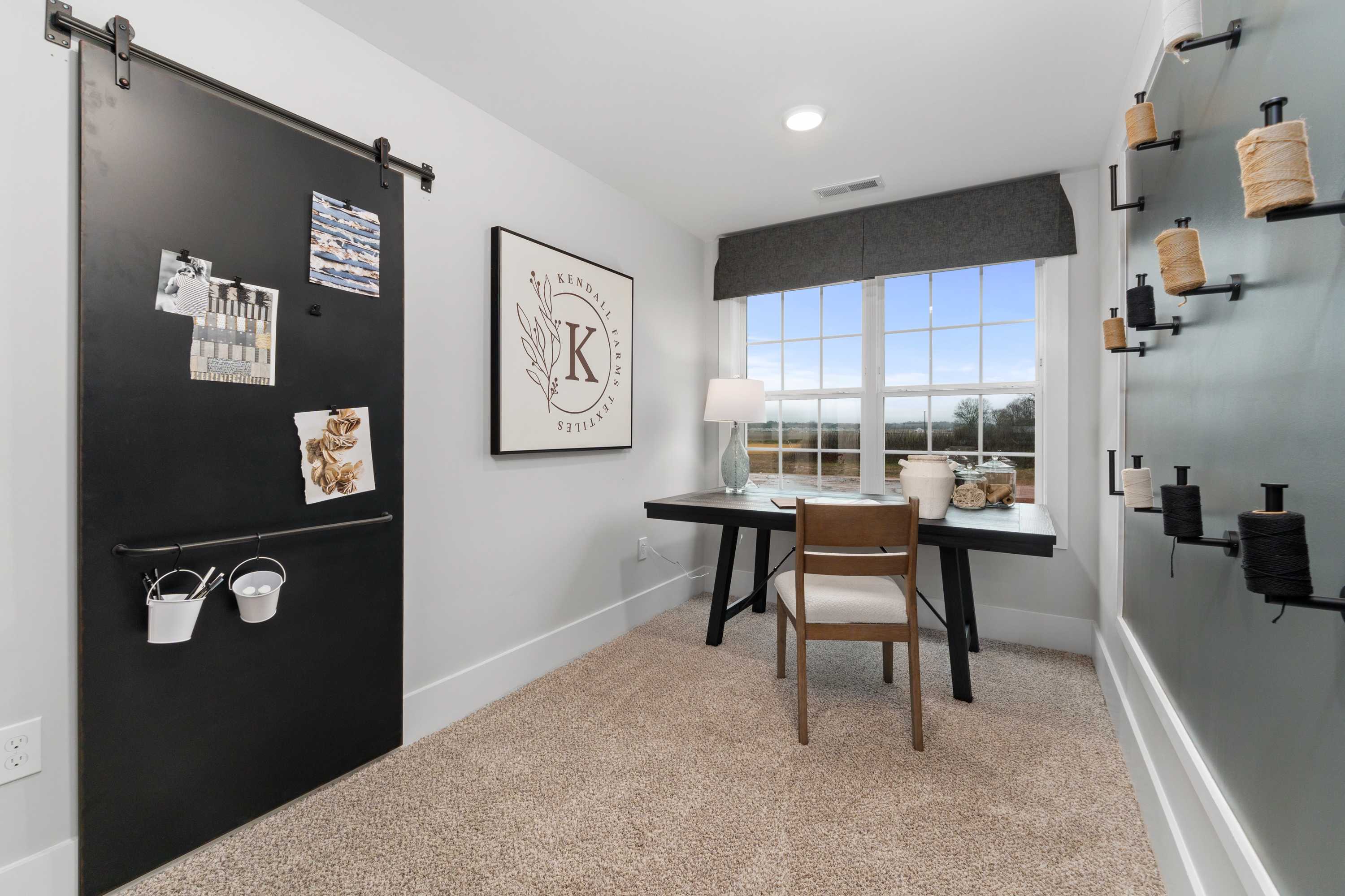 Cozy home office at Kendall Farms in Toney AL with sliding black barn door, wooden desk, chair, and large window view