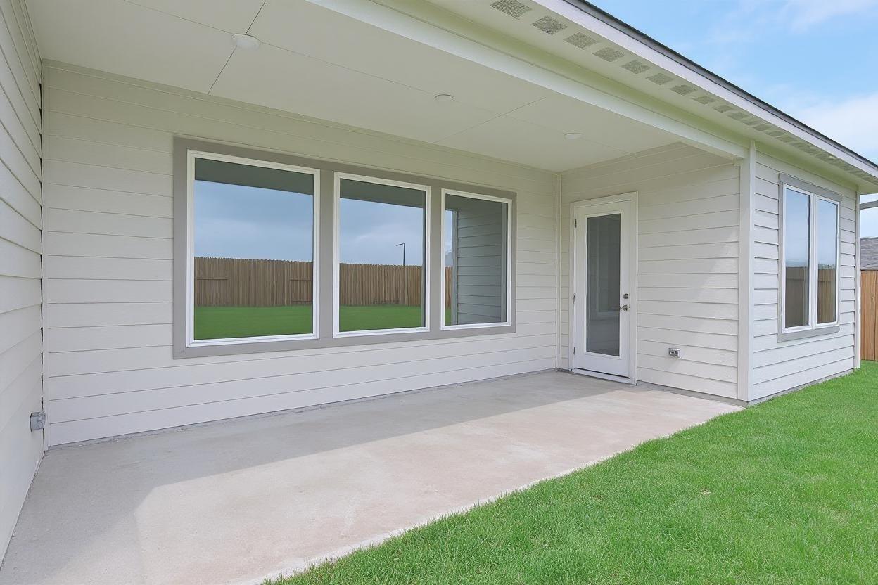 Covered patio with large triple windows and concrete floor overlooking green yard in Davidson Homes Edward A, Lago Mar, Texas City