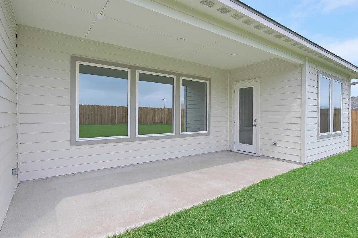 Covered patio with large triple windows and glass door overlooking lush green yard in Davidson Homes The Edward A, Lago Mar, Texas City
