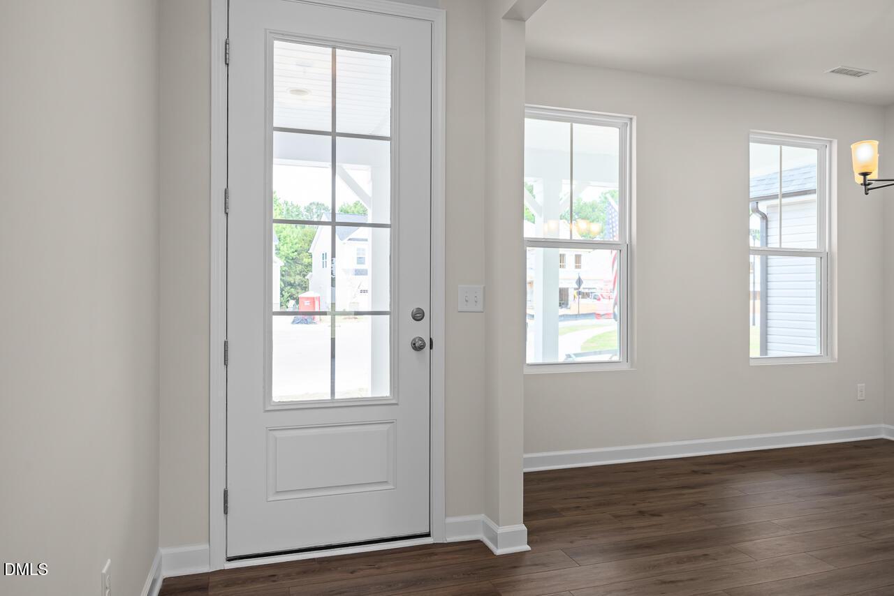 White glass-paneled front door in a bright, open-concept home at Woodland Crossing in Zebulon, NC by Davidson Homes.