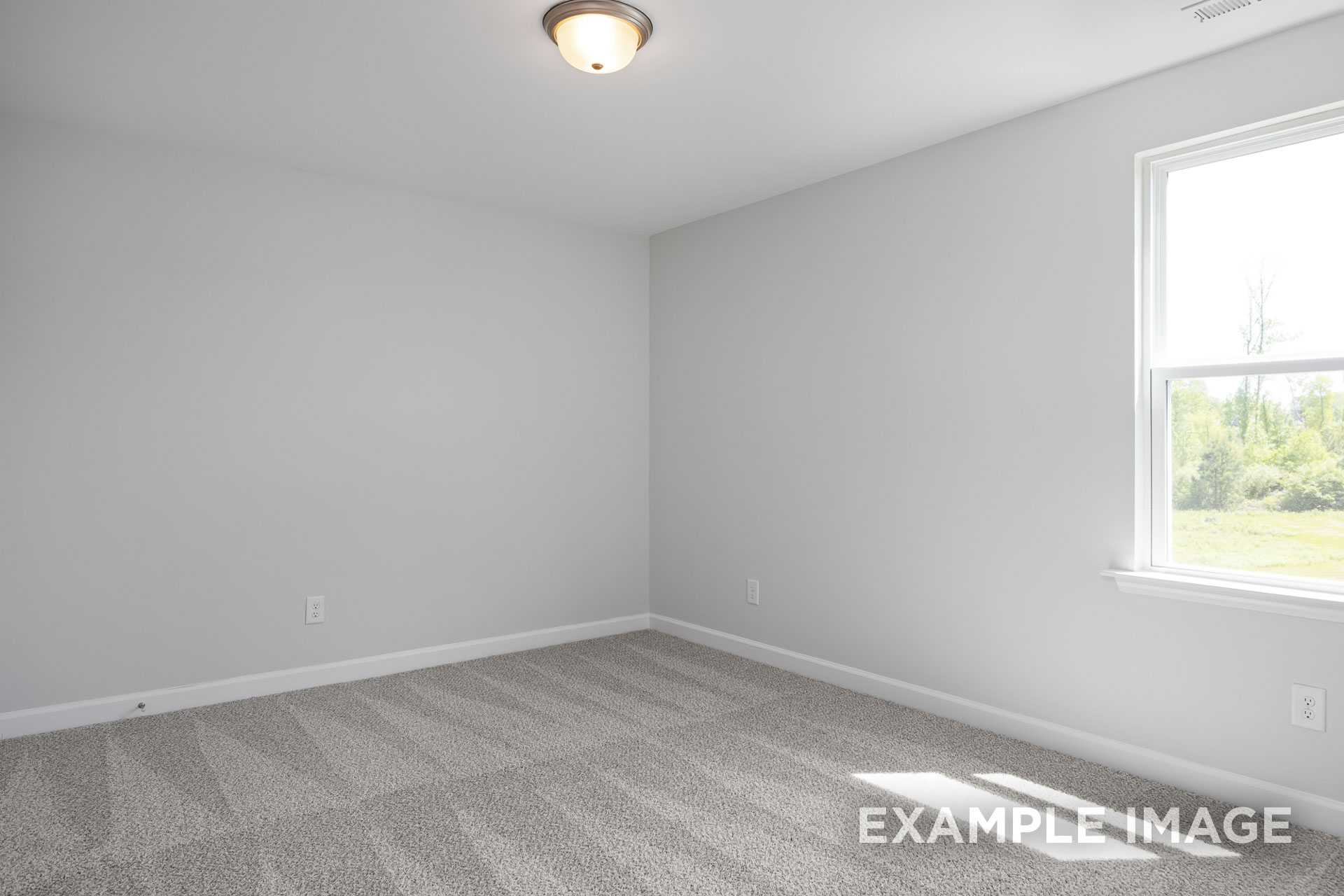 Spacious upper floor bedroom in The Grace C home with light gray walls, gray carpet, and sunlit window