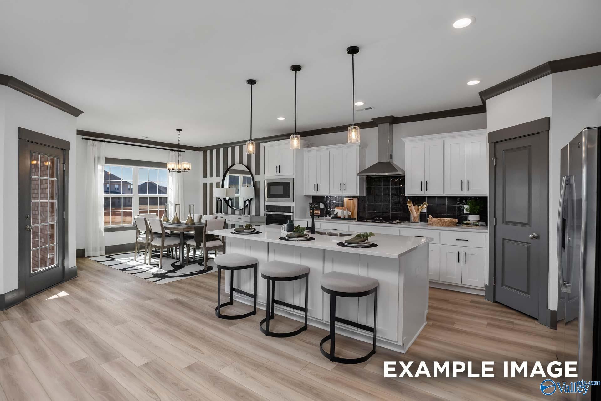 Spacious open-concept kitchen with white shaker cabinets, stainless appliances, island bar, and dining area in Davidson Homes The Rockford B, Madison, AL