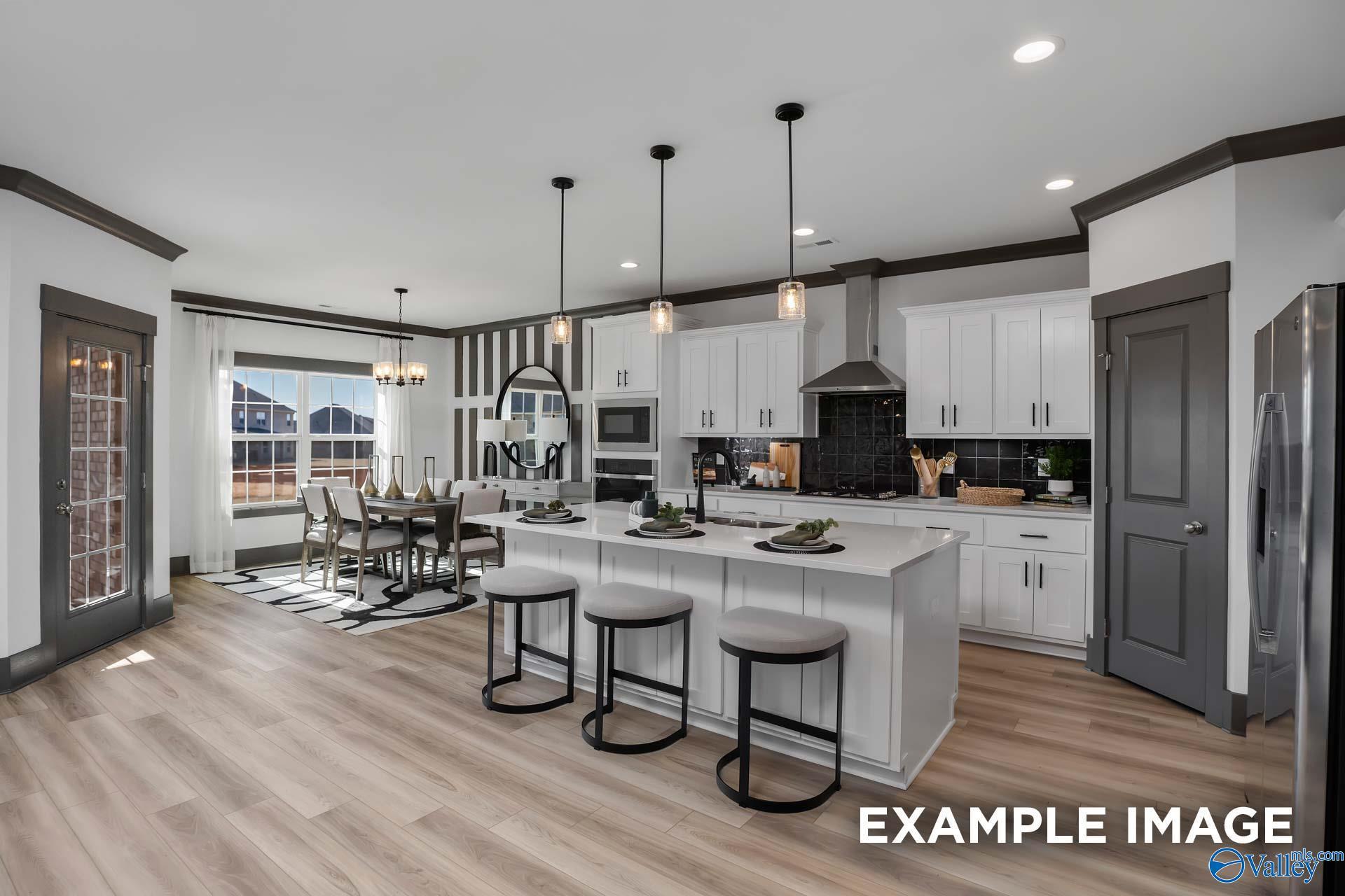 Spacious open-concept kitchen with white shaker cabinets, stainless appliances, island bar, and dining area in Davidson Homes The Rockford B, Madison, AL