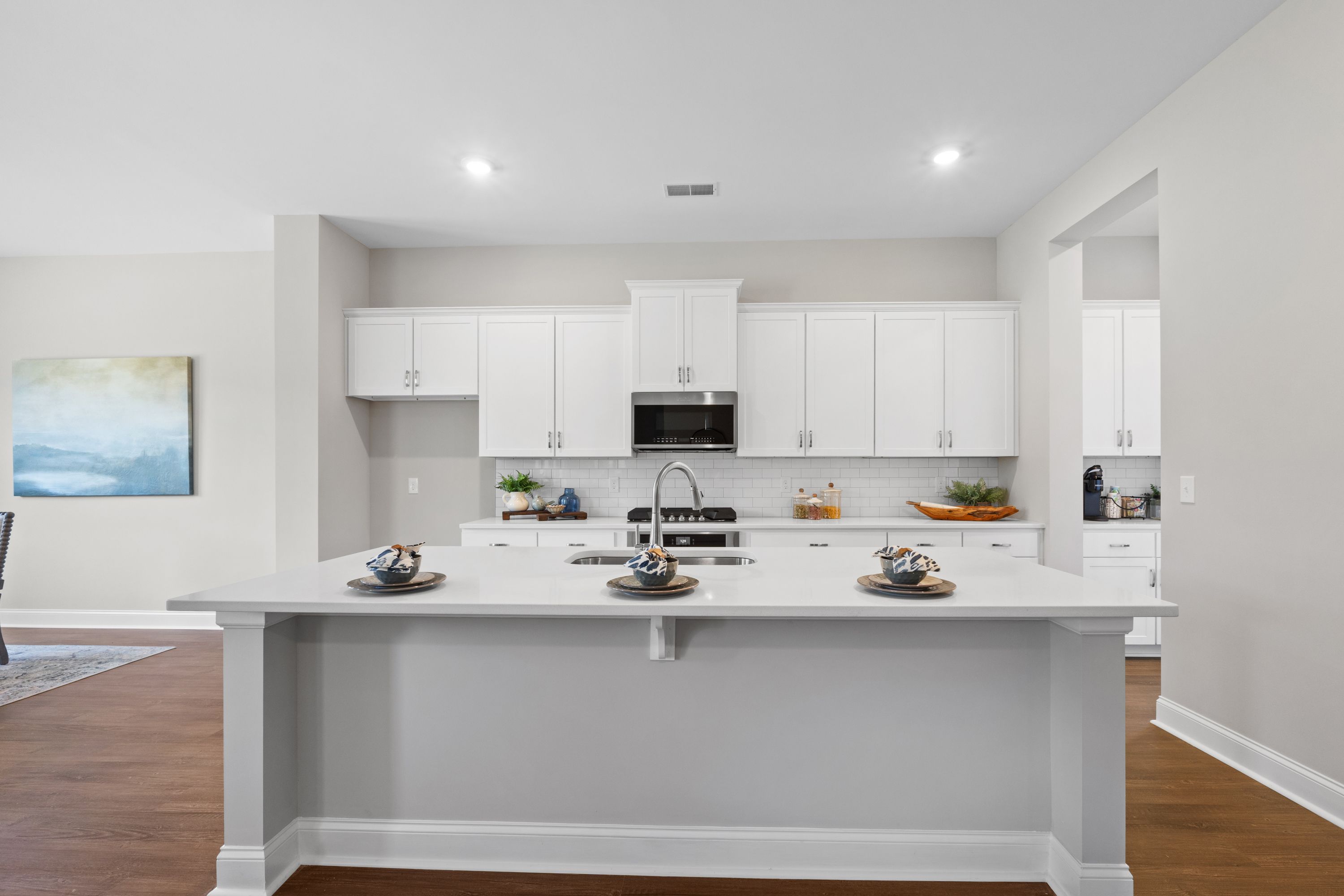 Spacious gourmet kitchen in The Haven D featuring white shaker cabinets, large quartz island with farmhouse sink, and open-concept layout
