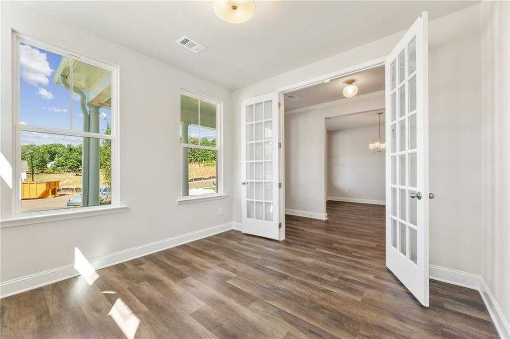 Bright living room with hardwood floors, large sunny windows, and open French doors in Davidson Homes The Danbury E, Buford, GA