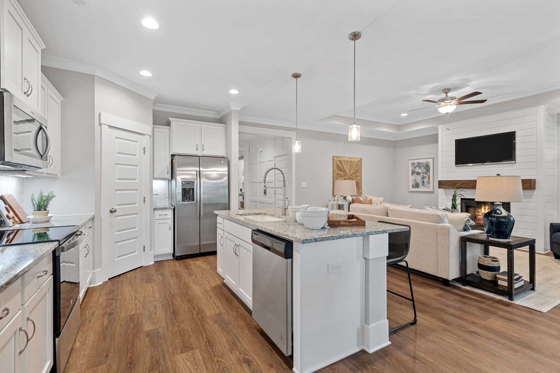 Spacious open-concept kitchen living room at Monteagle Cove in Owens Cross Roads AL with white cabinets stainless appliances island hardwood floors and fireplace