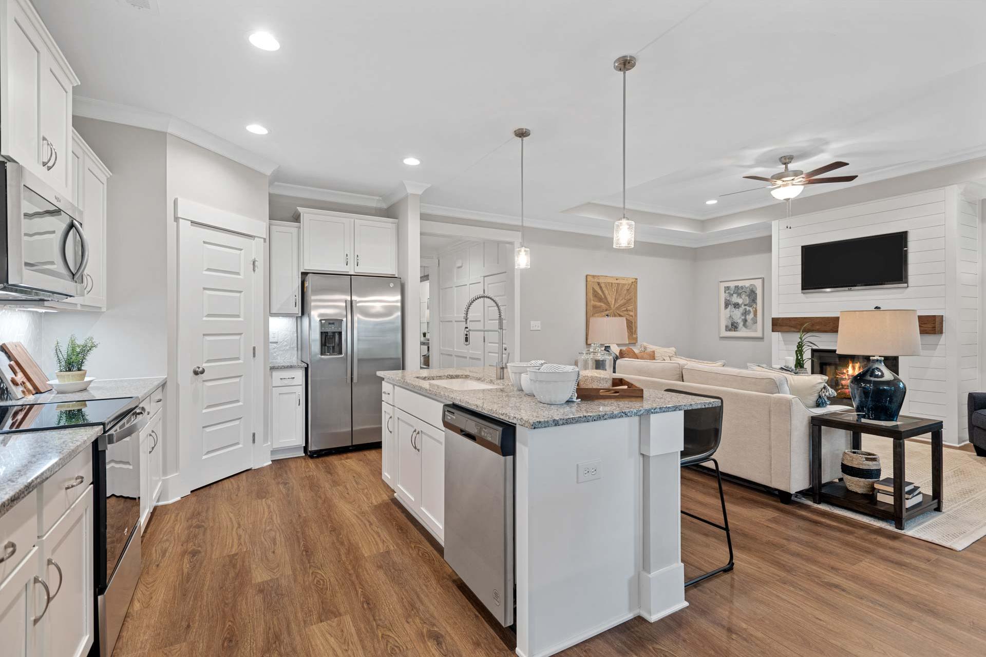 Spacious open-concept kitchen living room at Monteagle Cove in Owens Cross Roads AL with white cabinets stainless appliances island hardwood floors and fireplace