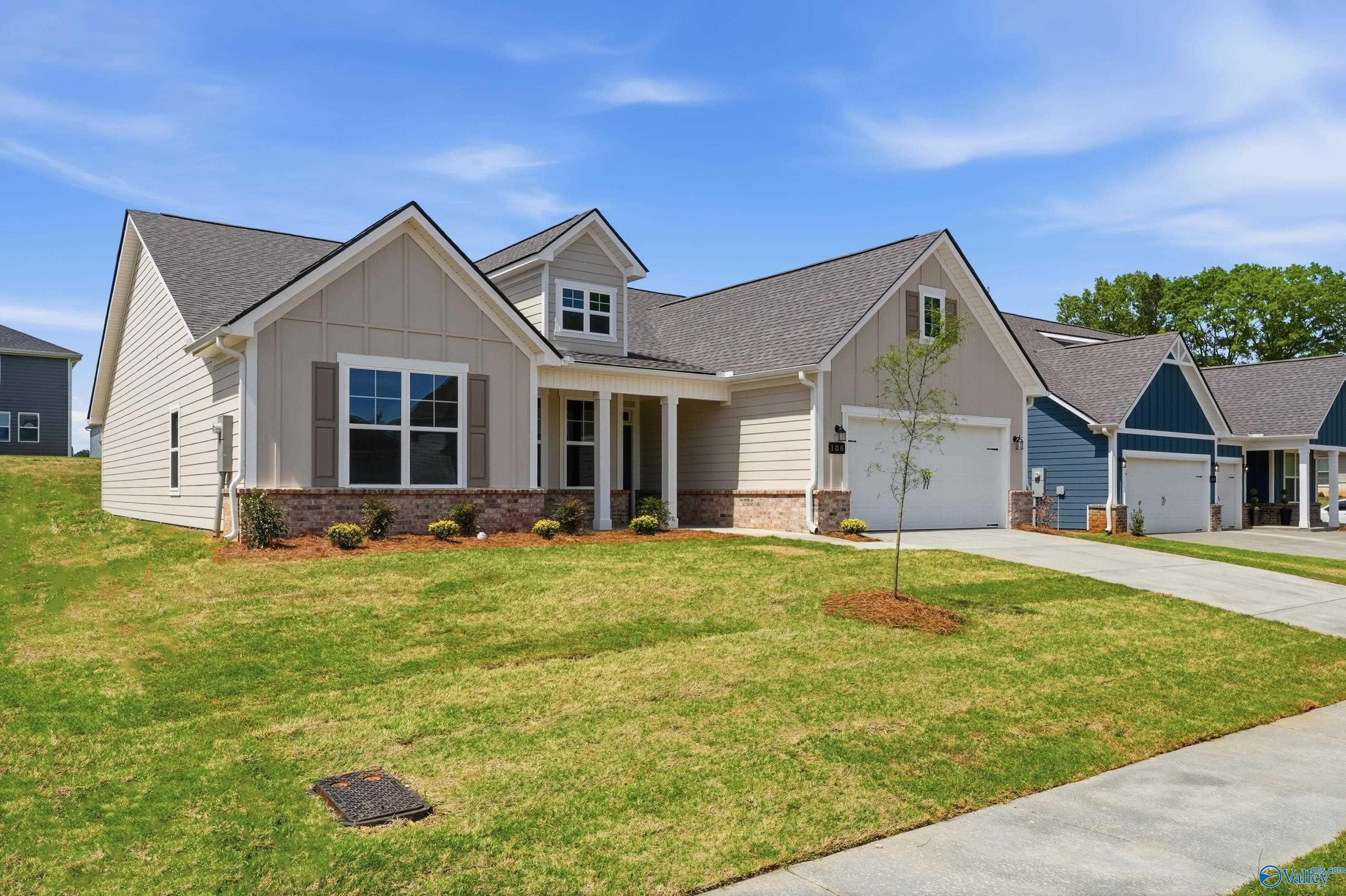 Modern beige single-story home with gabled roof, front porch, 2-car garage, and landscaped yard in Evergreen Mill, Madison, Alabama