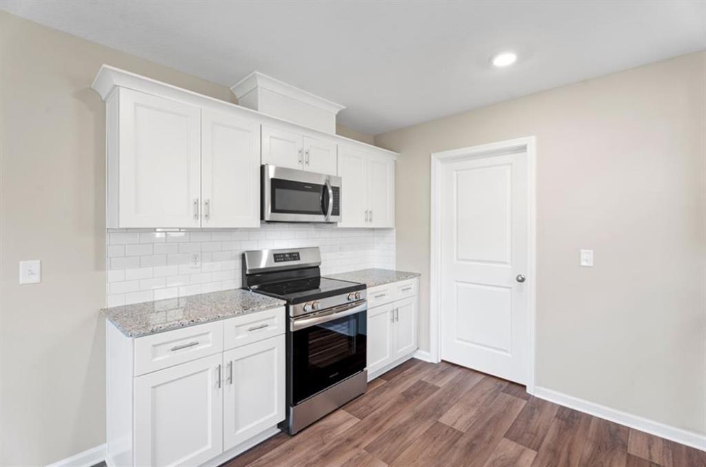 Modern kitchen with white shaker cabinets, granite countertops, stainless steel appliances and subway tile backsplash in Davidson Homes The Washington, Phenix City, AL