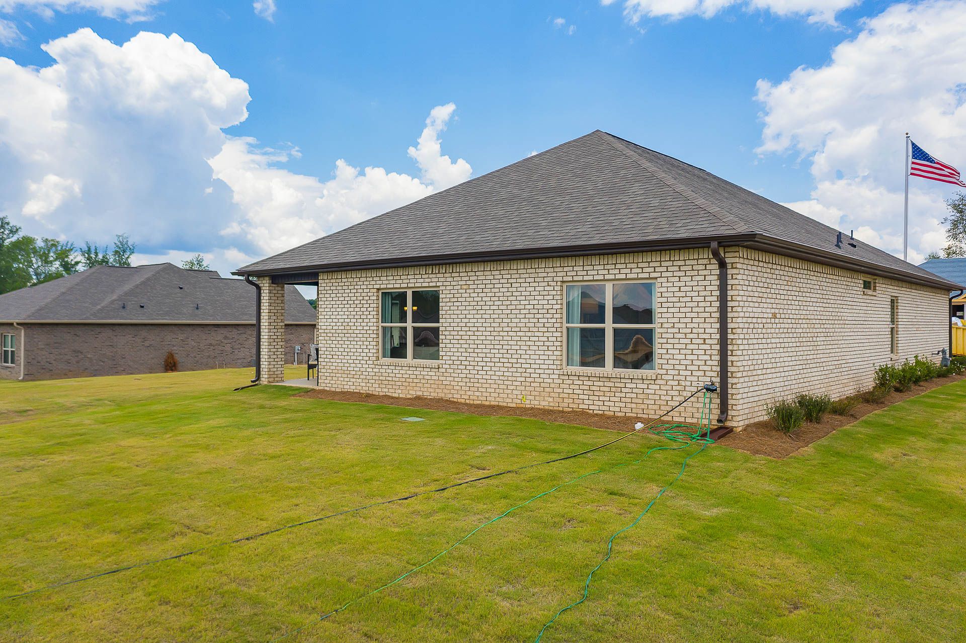 Brick home exterior at Heritage Heights in Madison, Alabama with gabled roof, windows, green lawn, and American flag