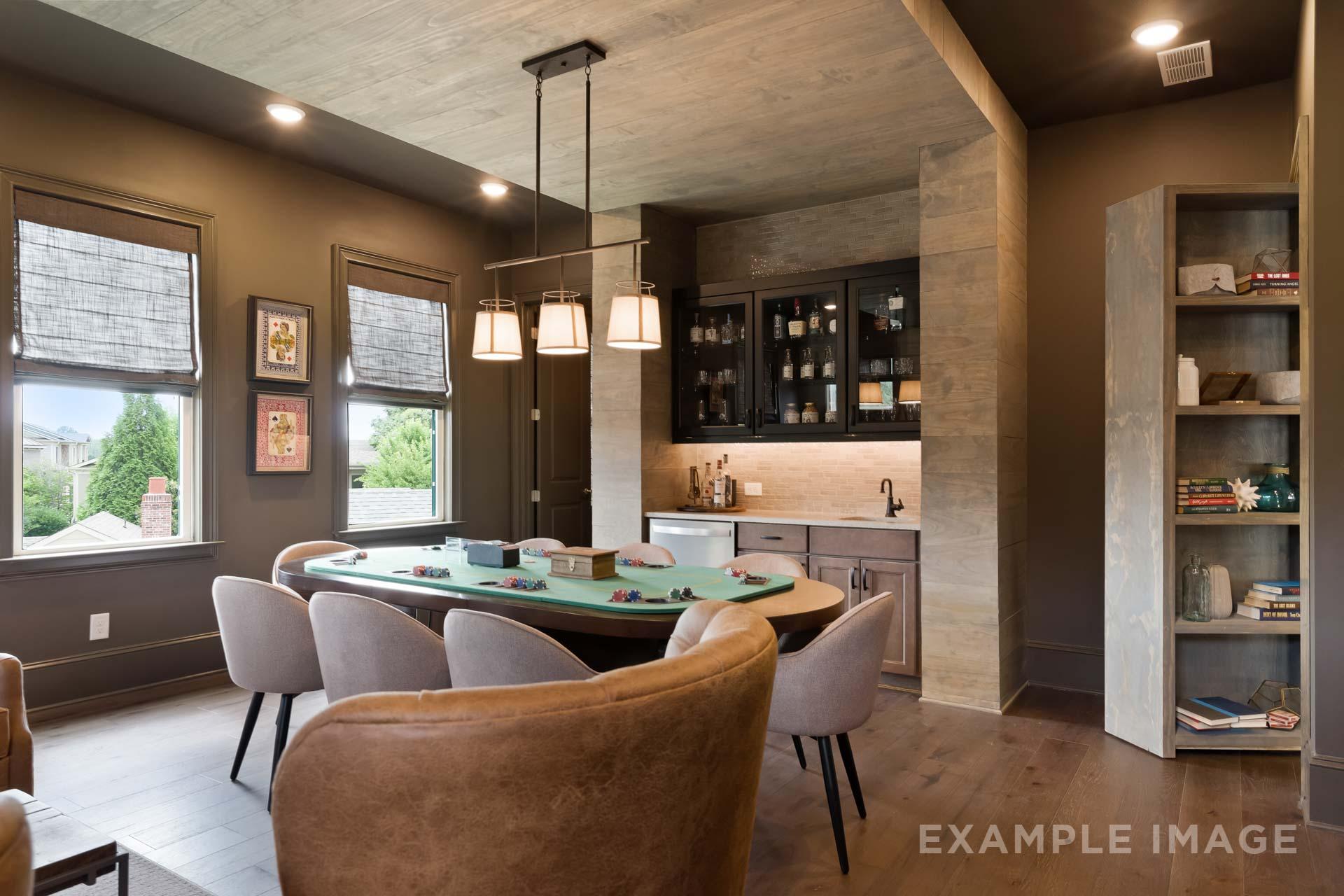 Cozy game room in The Seaside home design with oval pool table, leather chairs, and shiplap bar area