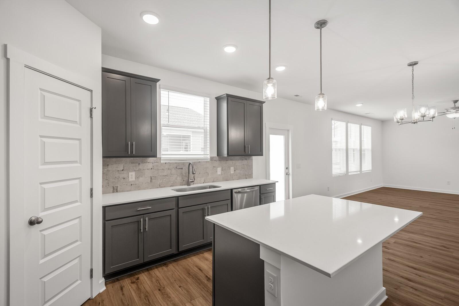 Modern kitchen with gray shaker cabinets, white quartz island, subway tile backsplash, stainless sink in Davidson Homes The Gordon C, White House, TN