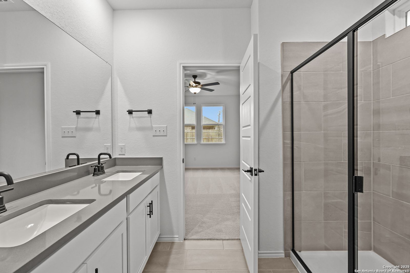 Modern master bathroom with dual quartz vanities, frameless glass shower, and white cabinetry in Davidson Homes The Daphne J, Converse, Texas