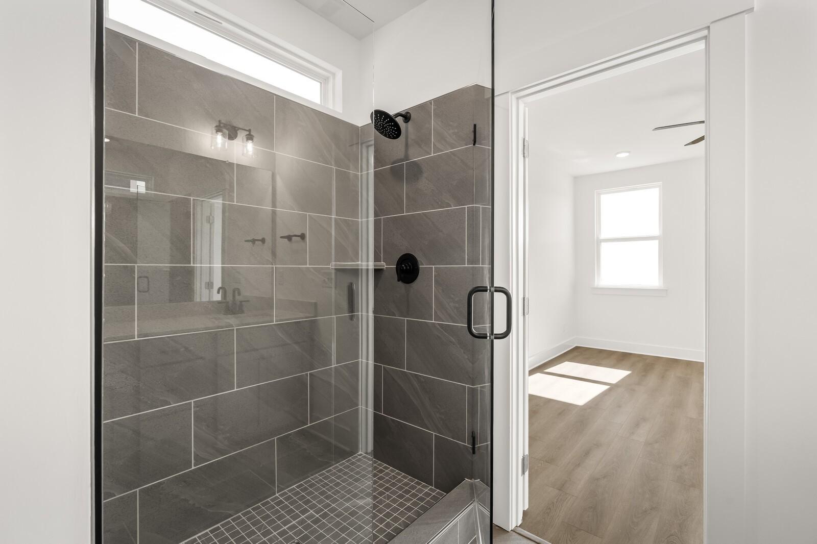 Modern walk-in shower with gray subway tiles, frameless glass door, and rainfall head in The Ash A master bath, Gallatin, TN