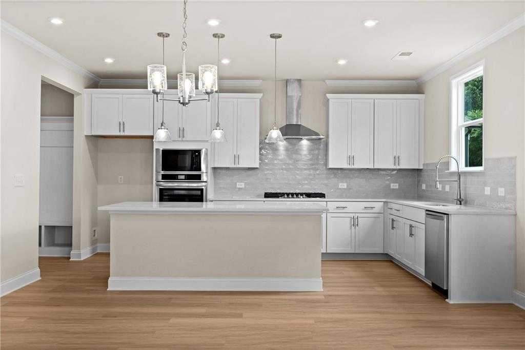 Modern white kitchen with center island, stainless appliances, subway tile backsplash in Davidson Homes The Hickory B at Wehunt Meadows, Hoschton