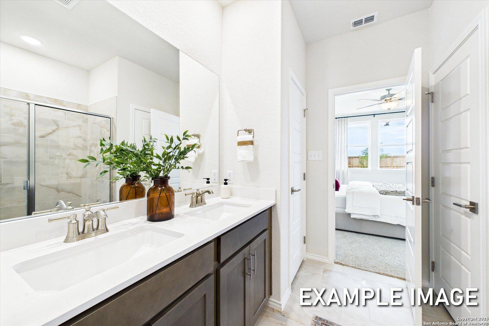 Modern master bathroom with double vanity, glass shower, and open bedroom view in Davidson Homes The Brazos C, Agave, San Antonio