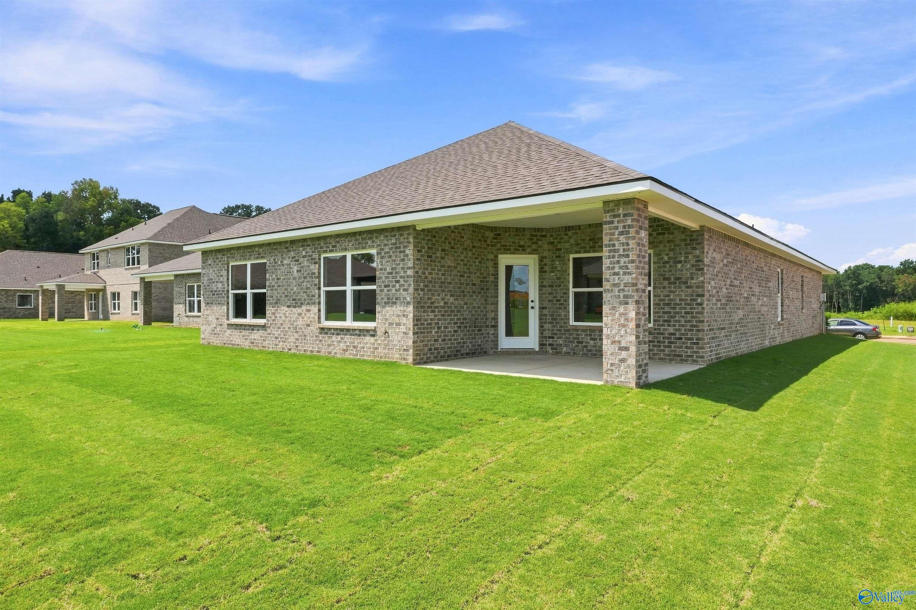 Brick exterior with covered patio and spacious backyard of The Everett B, 4-bedroom Davidson Homes plan in Wood Trail, Toney, AL