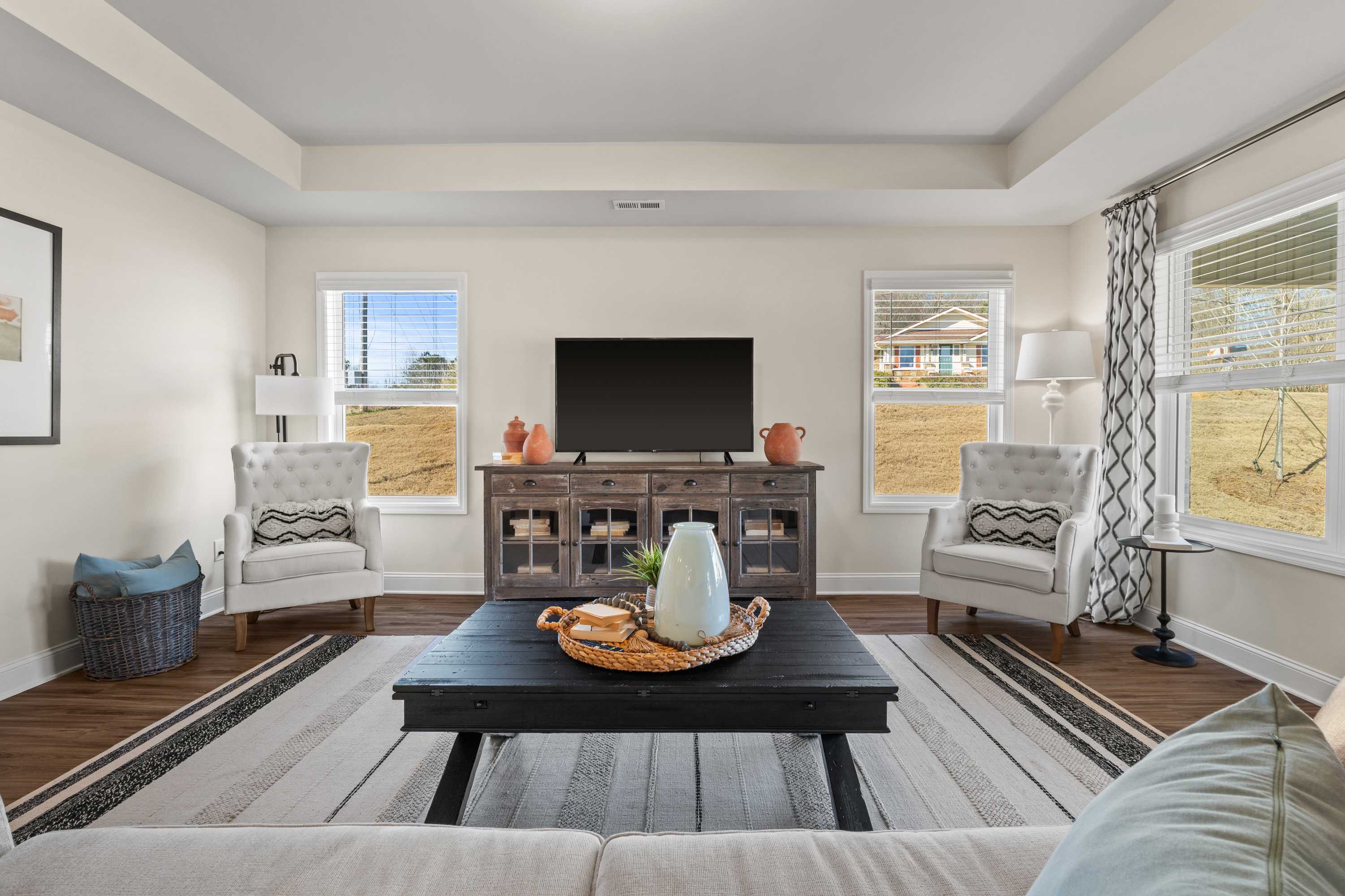 Spacious living room in Berry Cove, New Market, Alabama featuring hardwood floors, large windows with hill views, mounted TV, and neutral-toned furniture