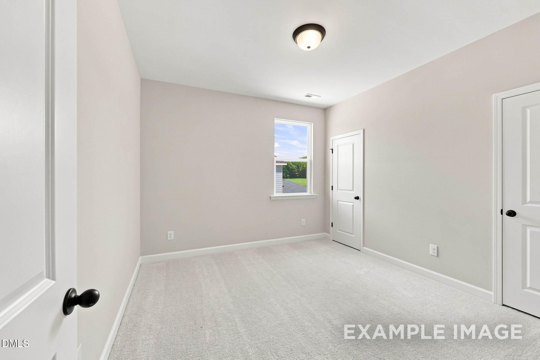 Bright carpeted bedroom with window and black hardware in Davidson Homes The Harris A, Forestville Yard, Knightdale, NC