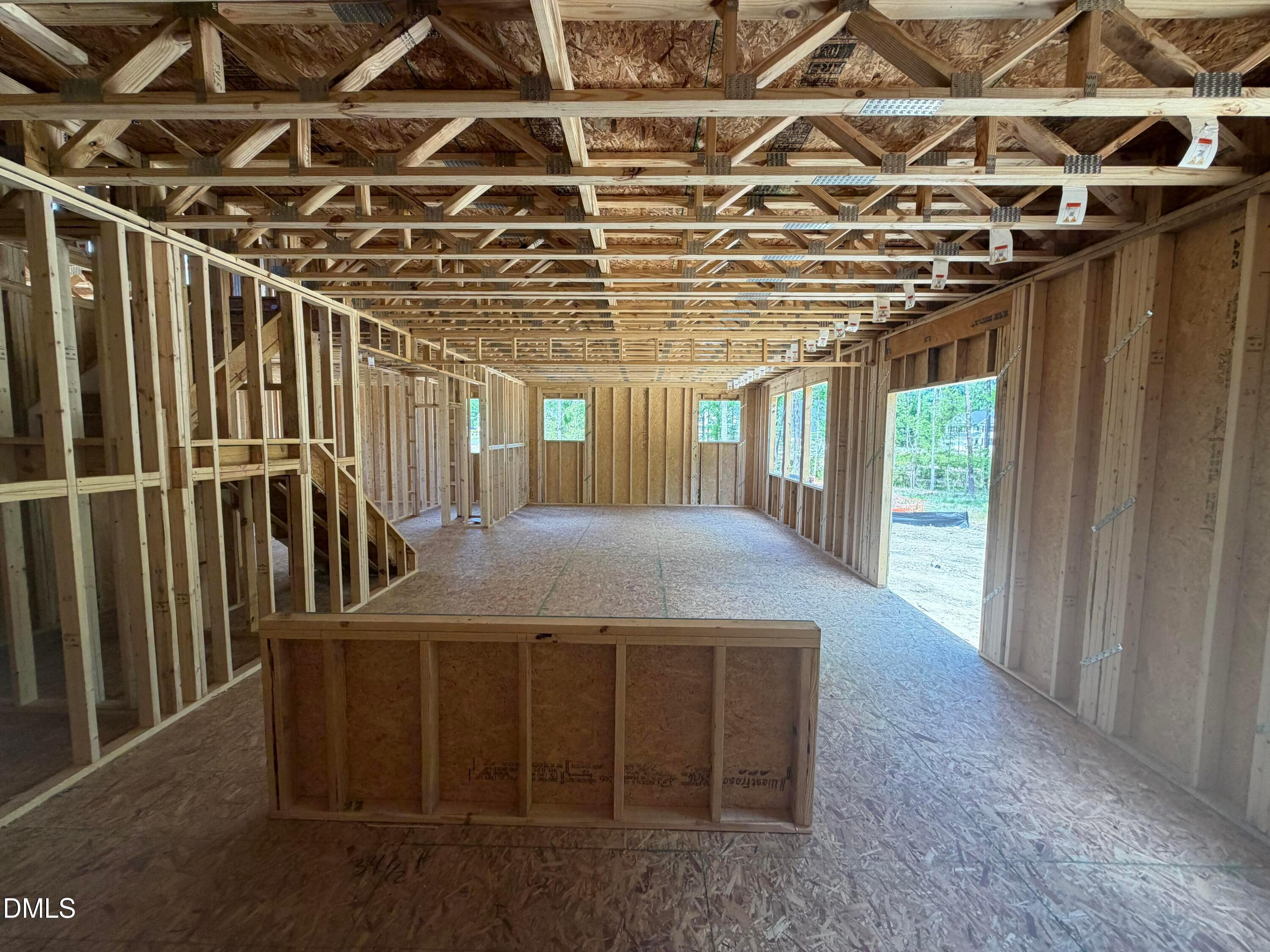 Interior wood framing of 2-story 4-bedroom home with exposed beams, staircase, windows, and open garage in Wellers Knoll, Lillington NC