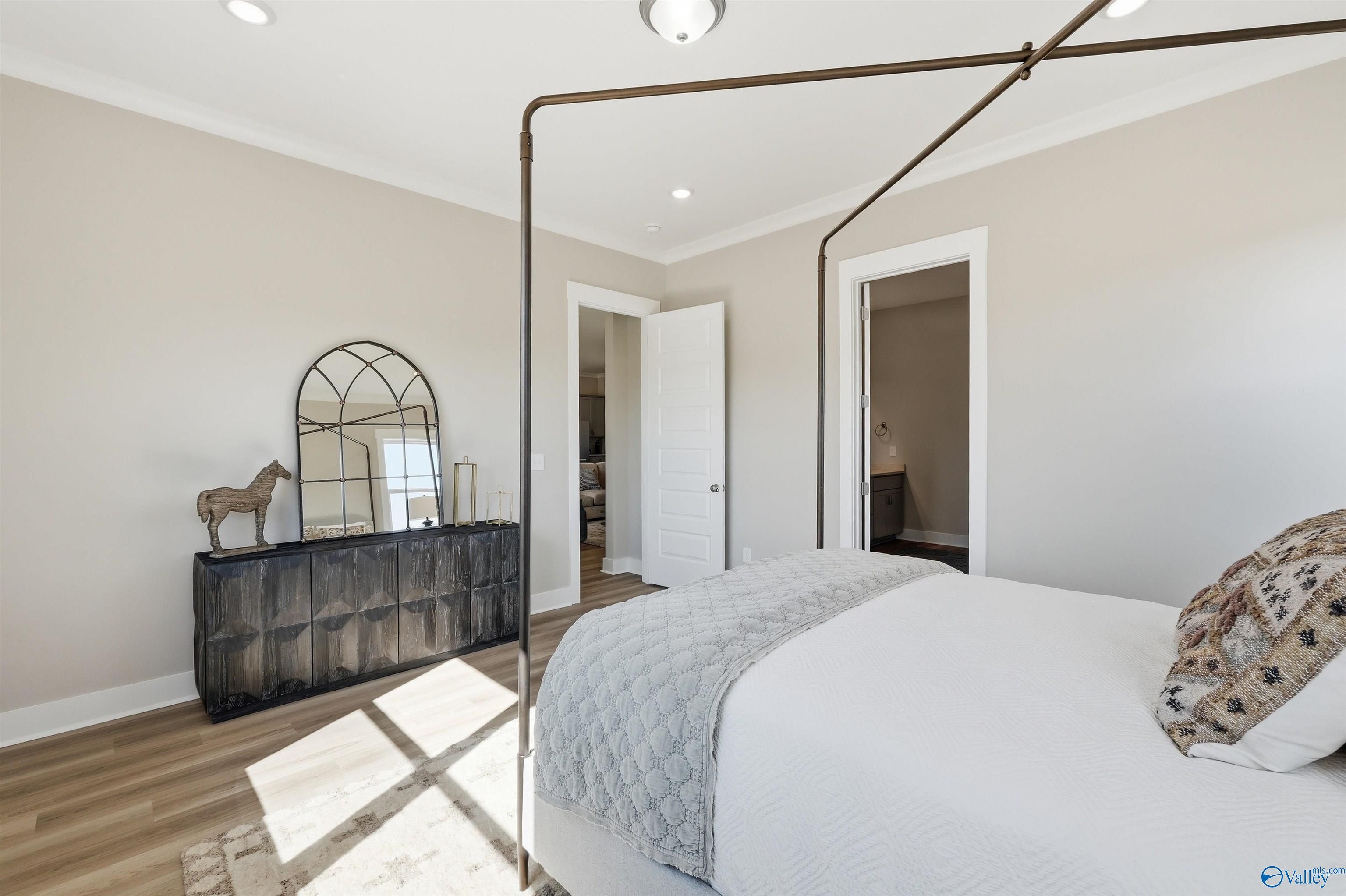 Elegant bedroom with canopy bed, arched mirror, horse statue, and en-suite door in Evermore Homes The Oxford B, Owens Cross Roads, AL