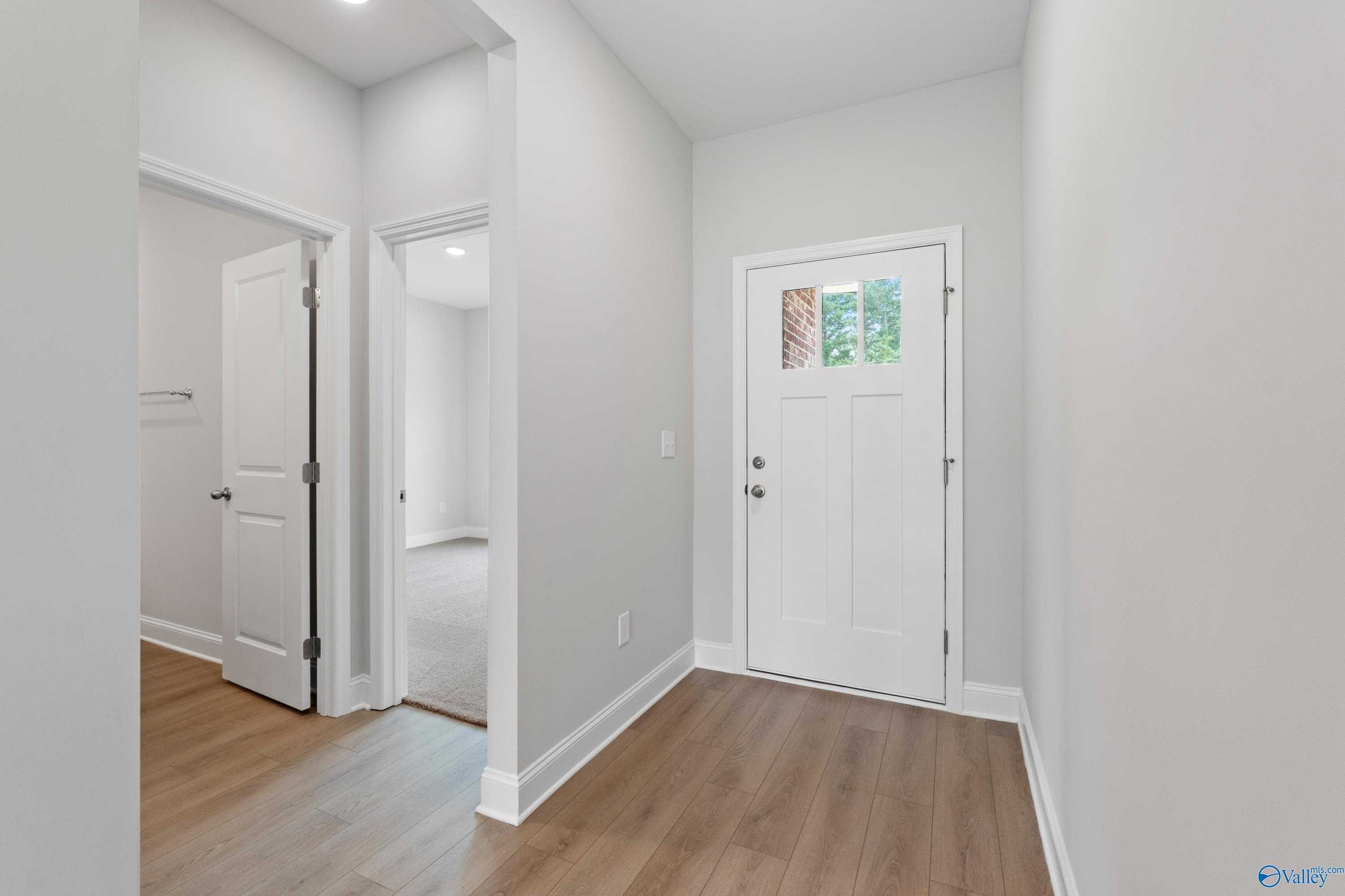 Welcoming entry foyer with white front door, gray walls, and hardwood floors in Davidson Homes The Franklin C, Harvest, Alabama