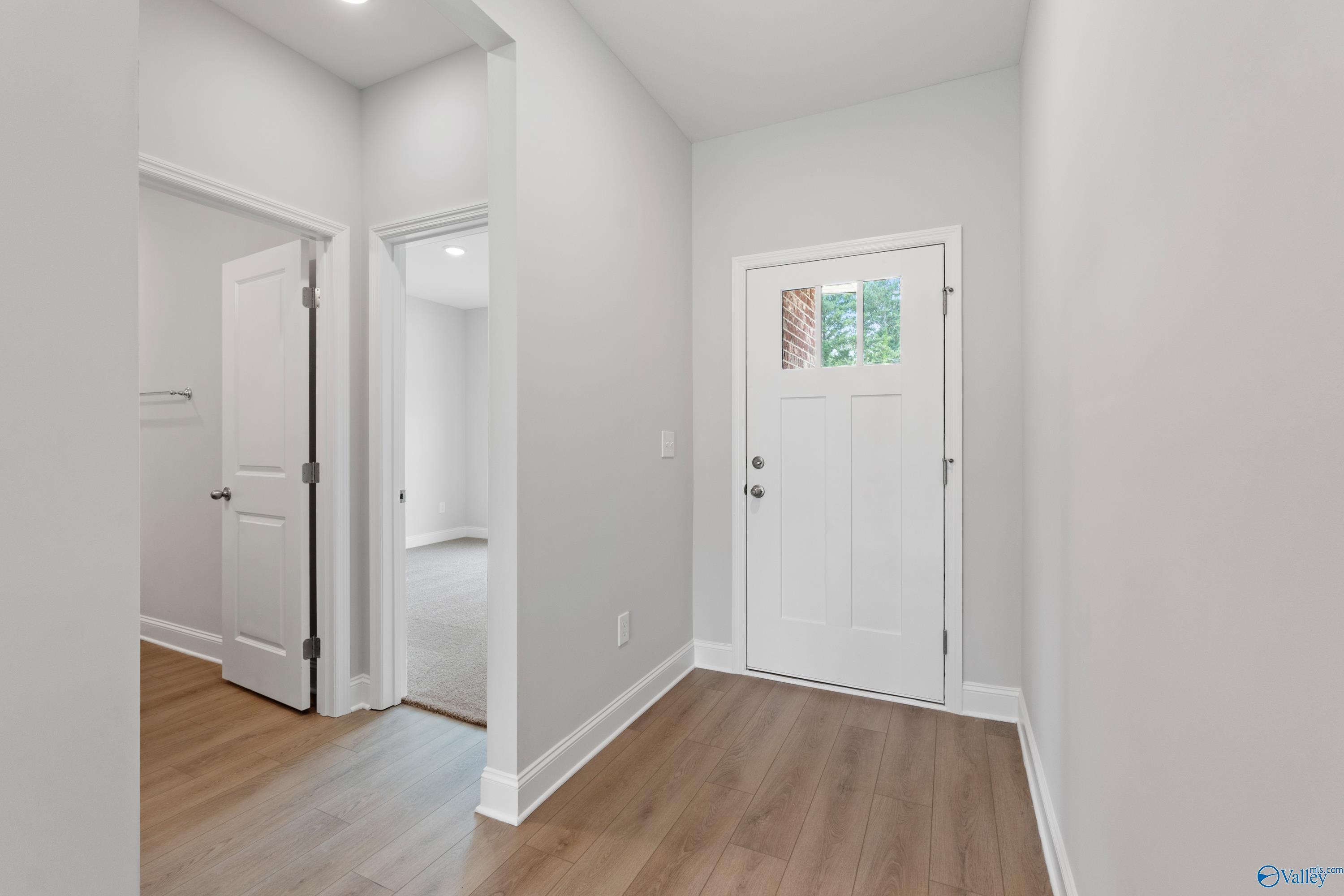 Welcoming entry foyer with white front door, gray walls, and hardwood floors in Davidson Homes The Franklin C, Harvest, Alabama
