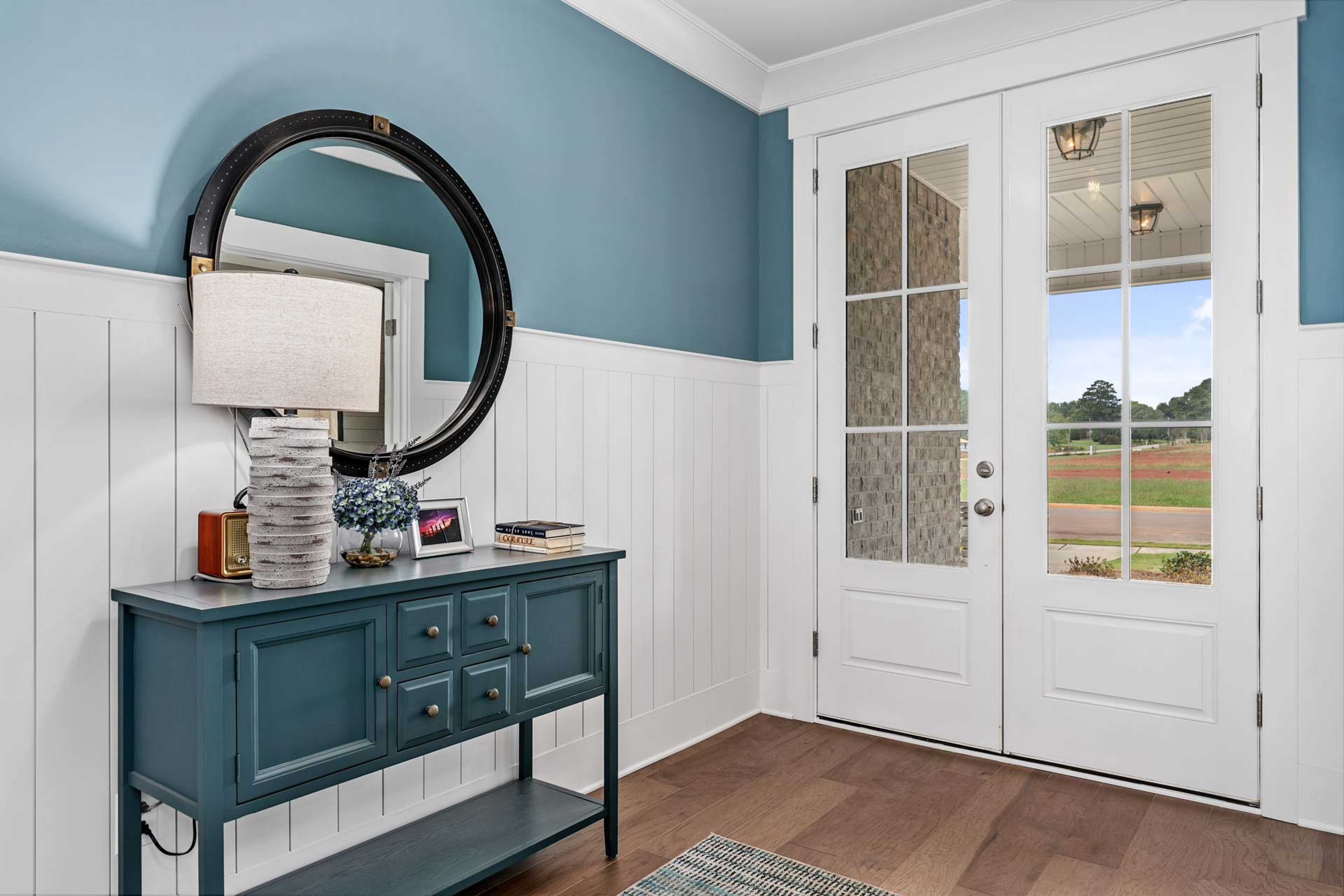 Elegant entryway foyer at Kendall Downs in Toney Alabama with blue shiplap walls, console table, and French doors to fields