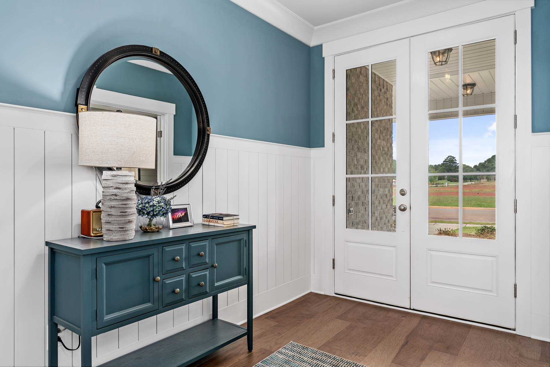 Elegant entryway foyer at Kendall Downs in Toney Alabama with blue shiplap walls, console table, and French doors to fields