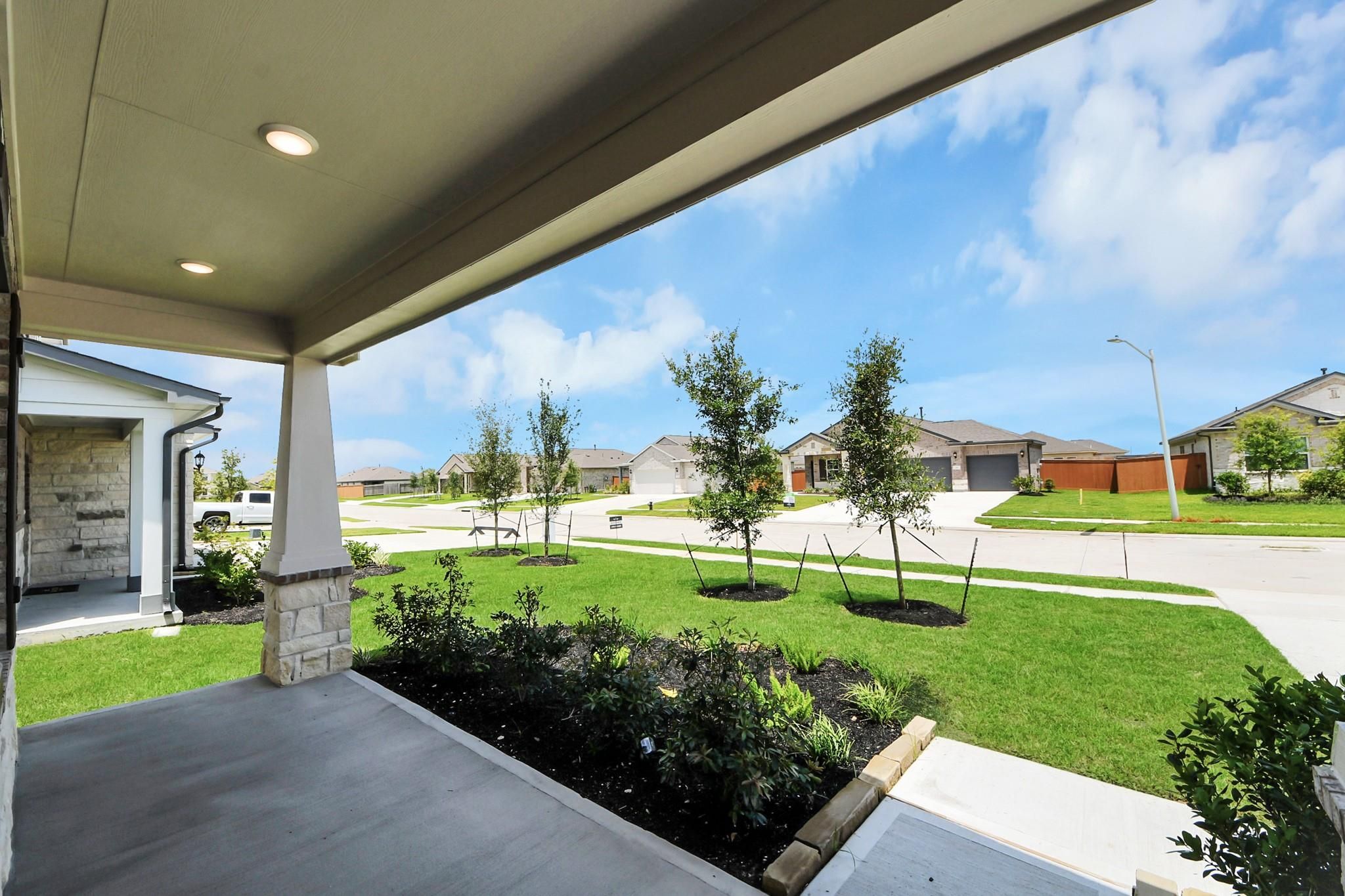 Covered front porch with stone columns overlooking landscaped yard in Davidson Homes' The Everett C, River Ranch Meadows, Dayton, Texas