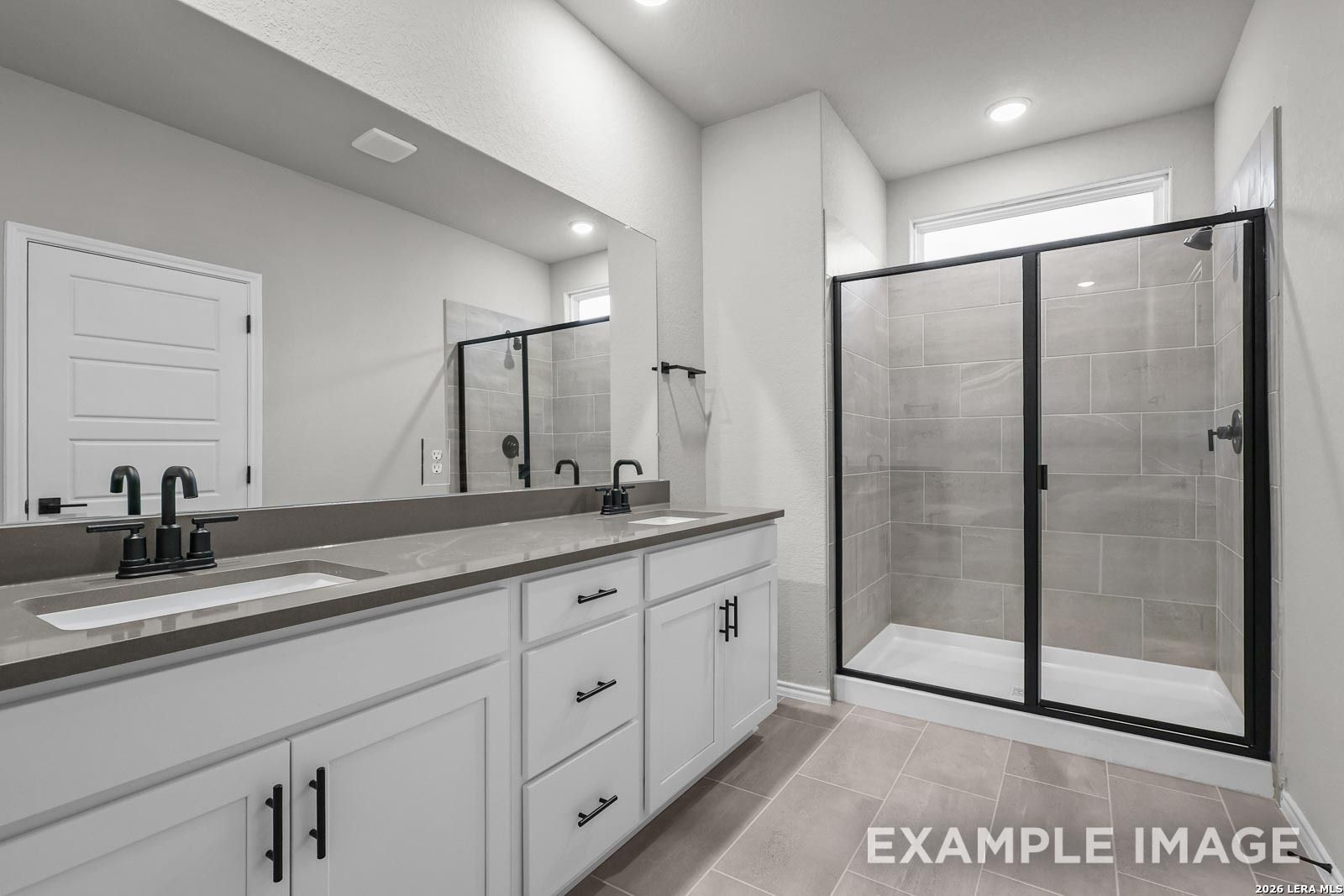 Modern bathroom with dual vanity, quartz countertops, and walk-in shower in The Glenwood E home at Royal Crest, San Antonio.