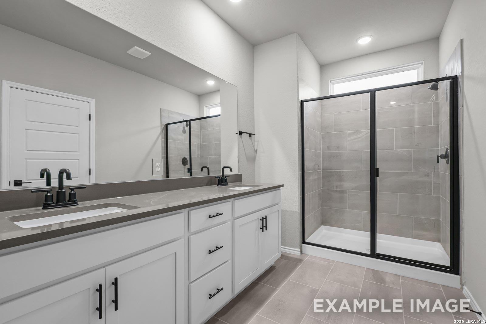 Modern bathroom with dual vanity, quartz countertops, and walk-in shower in The Glenwood E home at Royal Crest, San Antonio.