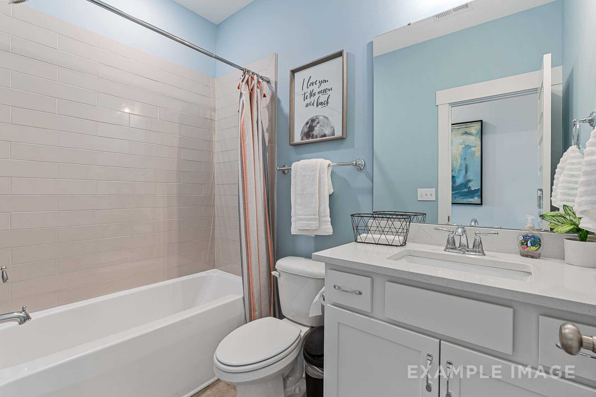 Serene master bathroom in The Rockford with light blue walls, soaking tub, orange shower curtain, and white vanity sink