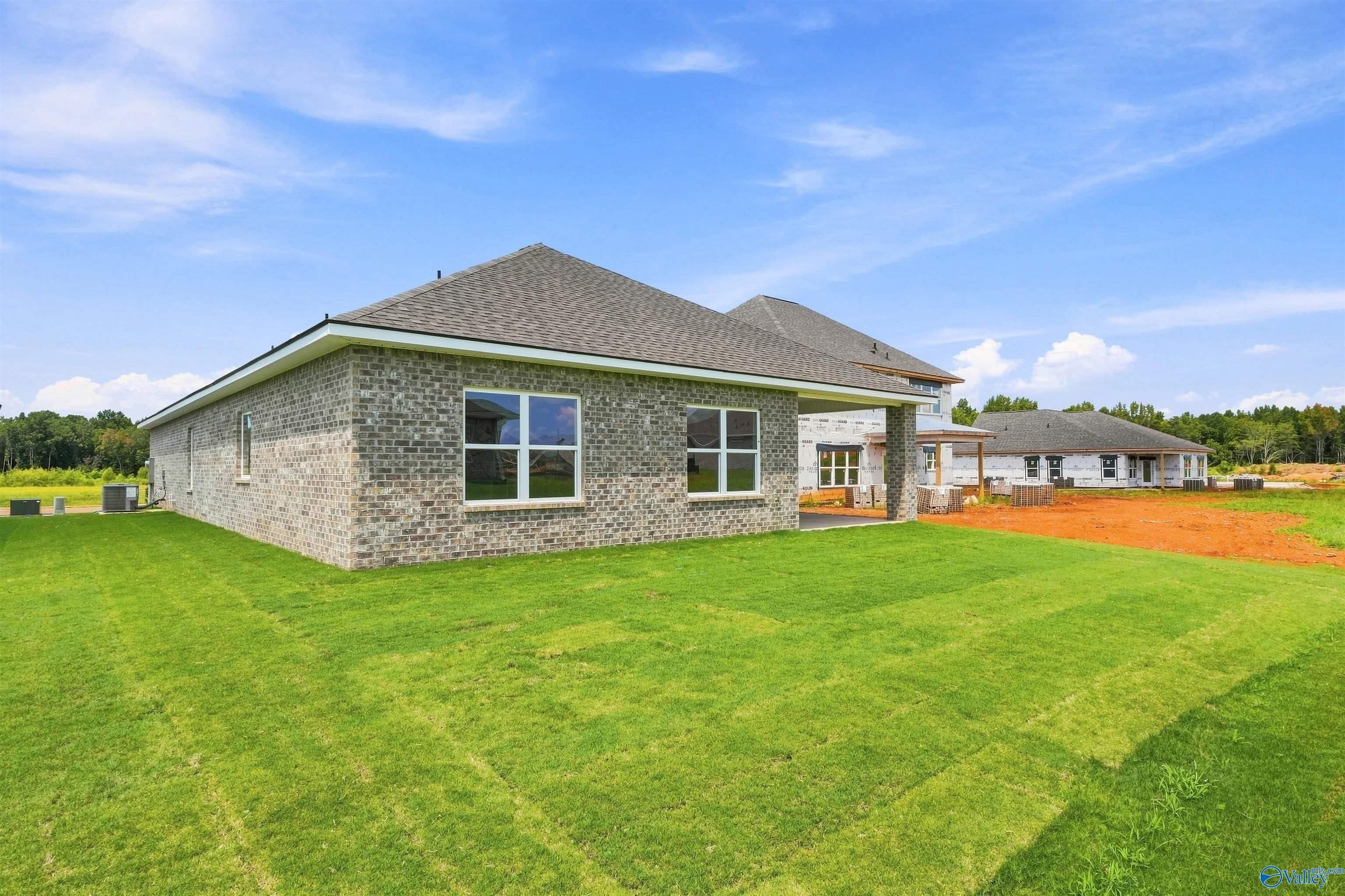 Brick exterior and covered patio of Davidson Homes' The Everett B plan in Wood Trail, Toney, Alabama with large fenced backyard.