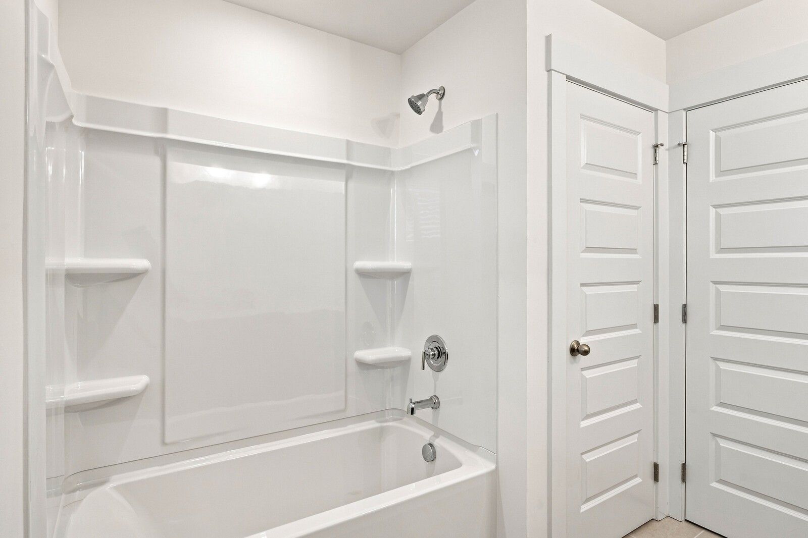 White tub/shower combo with built-in shelving and brushed nickel fixtures in Davidson Homes The Willow C bathroom, Gallatin, TN