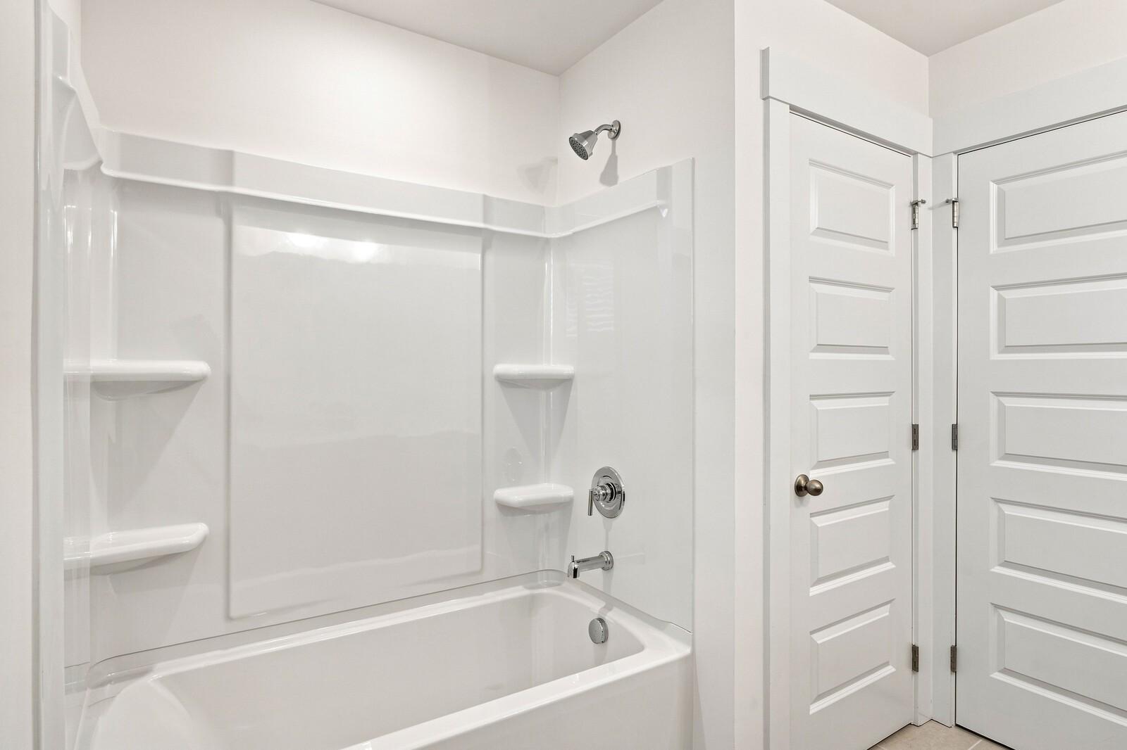 White tub/shower combo with built-in shelving and brushed nickel fixtures in Davidson Homes The Willow C bathroom, Gallatin, TN