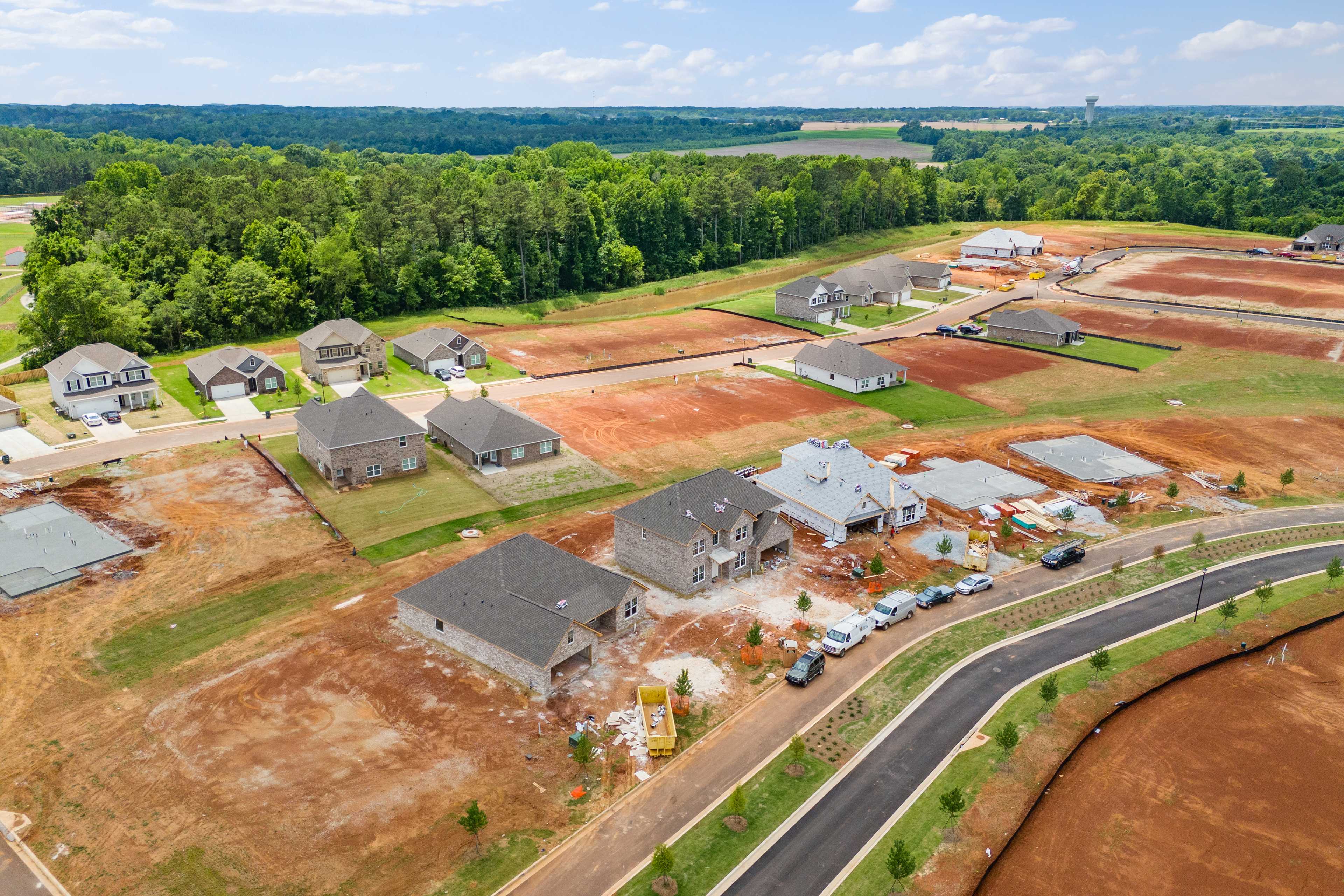 Aerial view of Creekside neighborhood in Harvest Alabama featuring new homes under construction amid wooded landscape