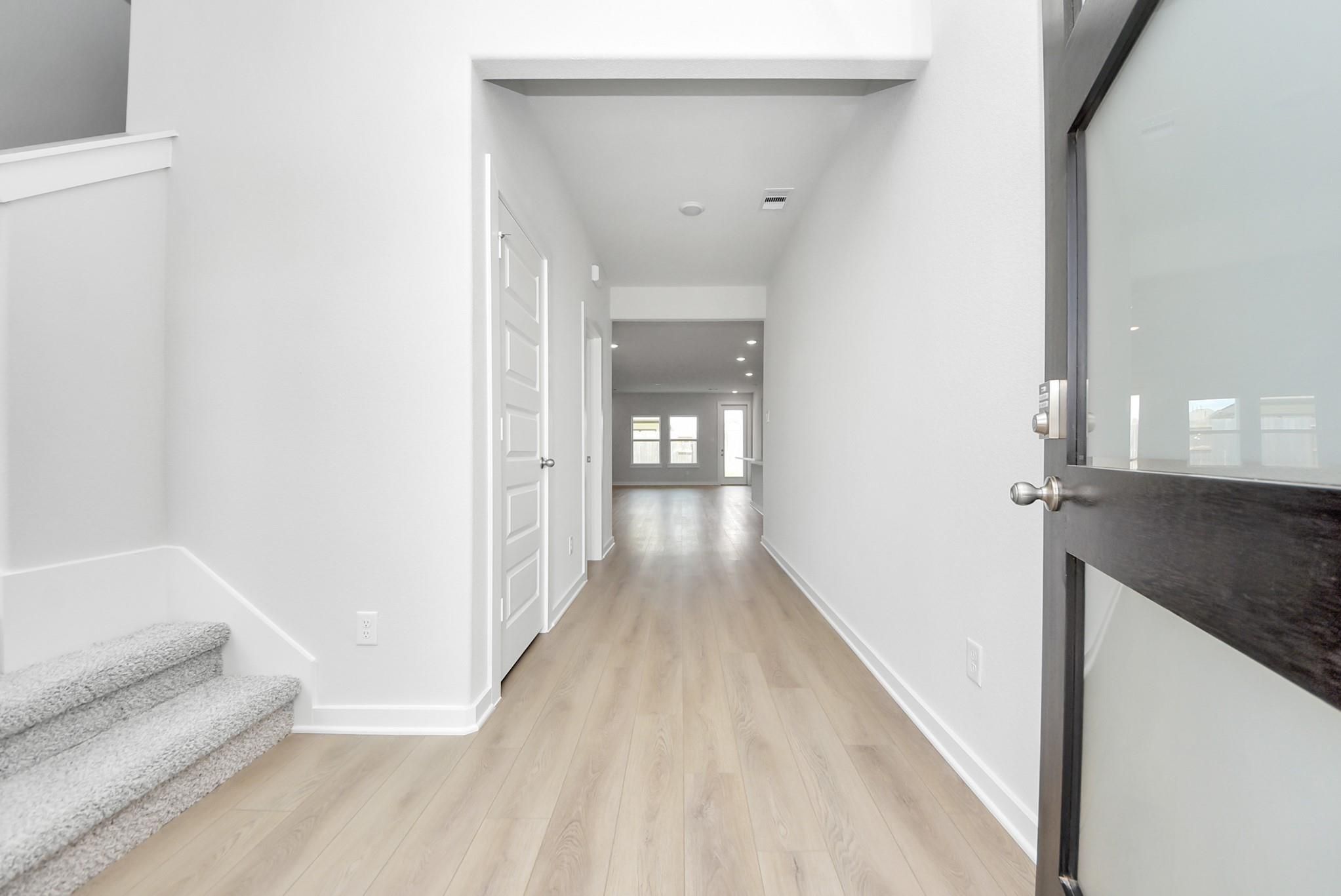 Bright foyer entry with wood-look flooring and staircase in The Verano B floor plan by Davidson Homes in Sunterra, Katy.