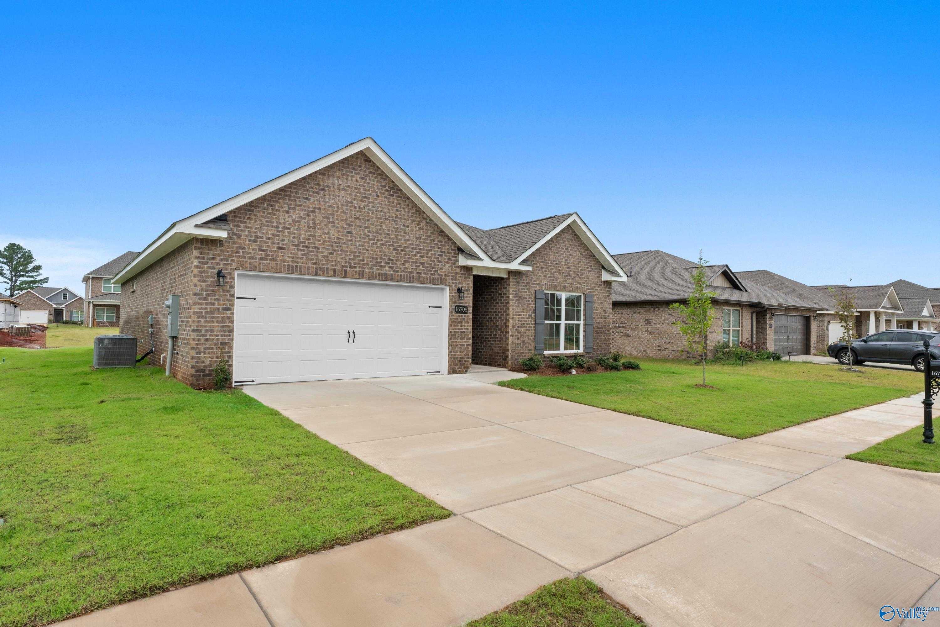 Brick 1-story home with 2-car garage, concrete driveway, green lawn, and blue sky in Davidson Homes The Asheville C, Ricketts Farm, Athens, Alabama