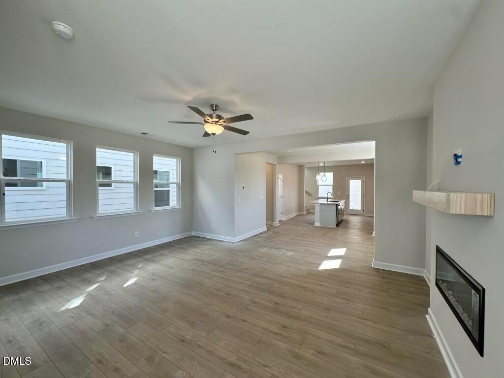 Bright open living room with gas fireplace, ceiling fan, hardwood floors in The Burke by Davidson Homes, Knightdale, NC