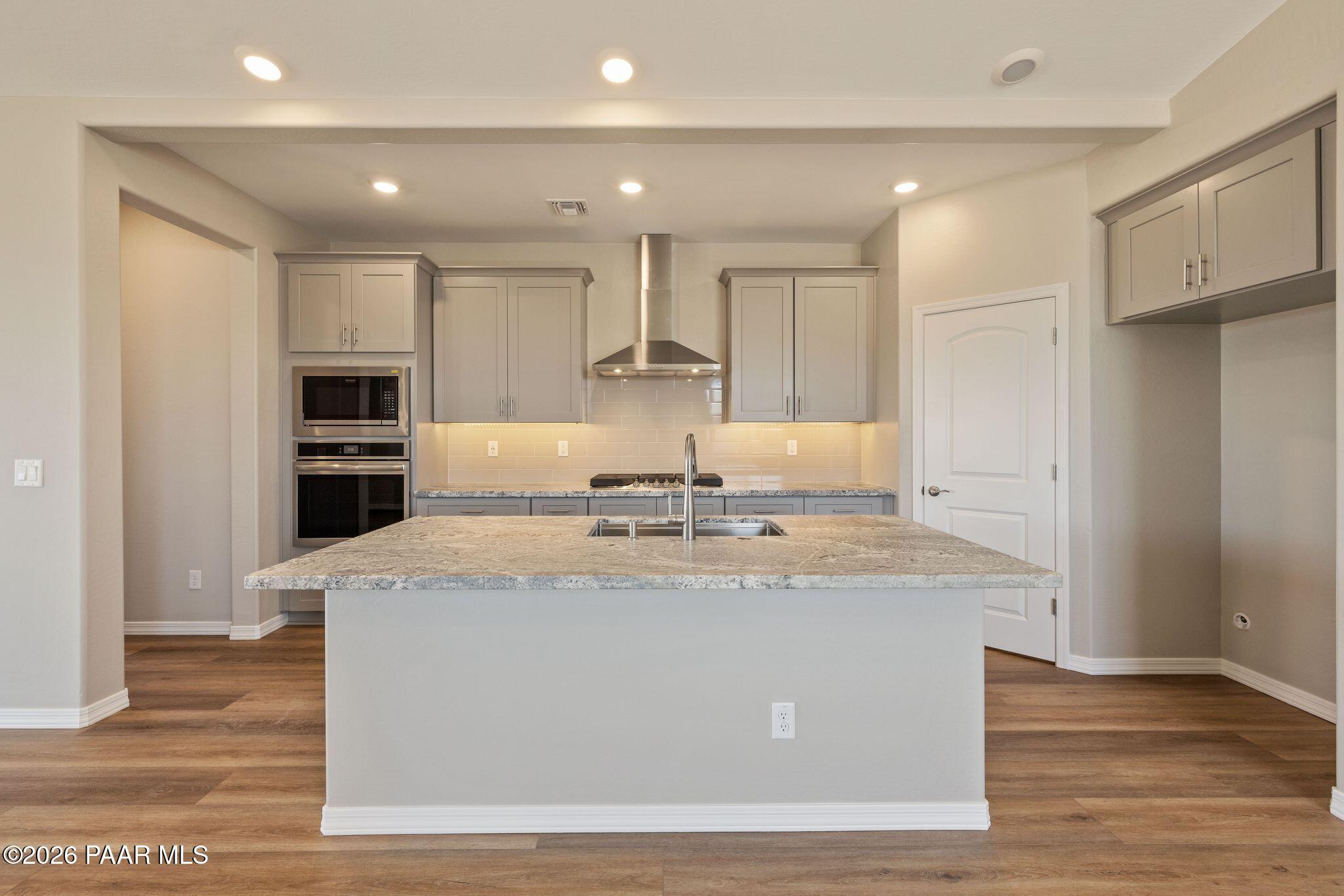 Modern kitchen featuring granite island sink, stainless steel appliances, and shaker cabinets in Davidson Homes The Frontier A, Prescott Valley, AZ