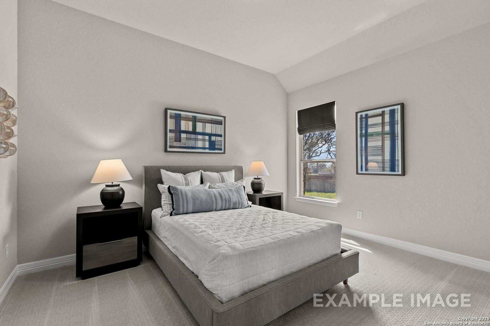 Tranquil master bedroom with gray platform bed, blue pillows, abstract art, and tree-view window in Davidson Homes The Summerlin B, Castroville