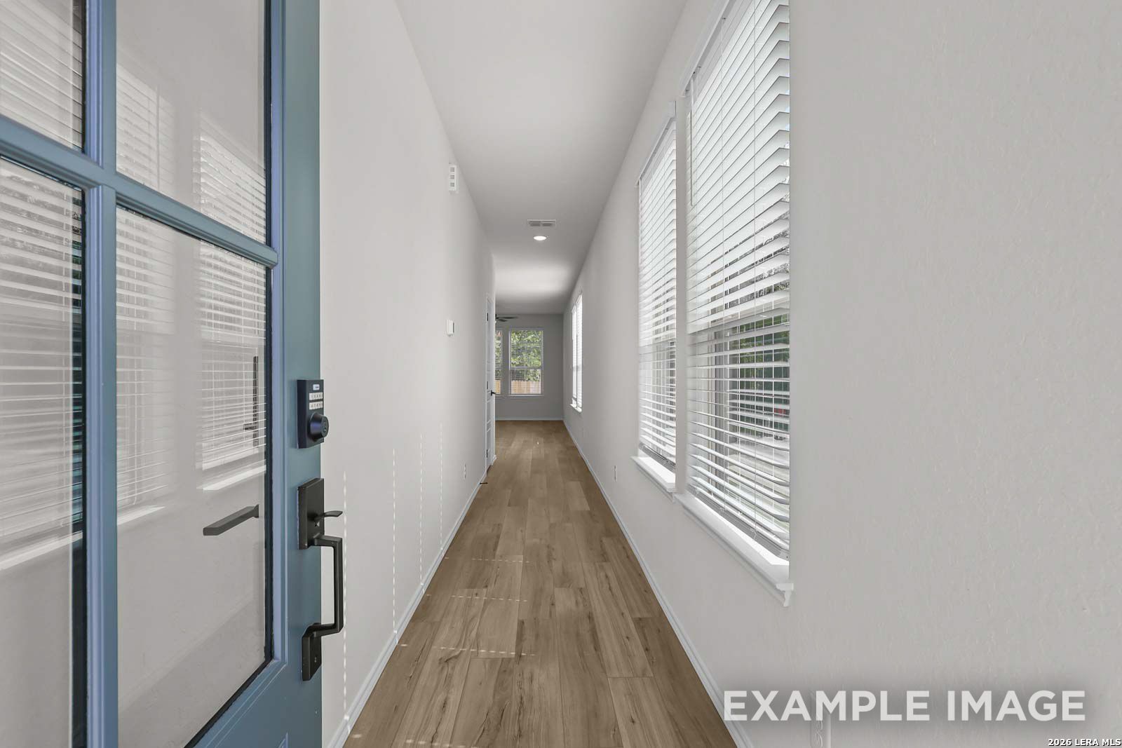 Bright entryway and hallway with wood-style flooring in The Florence A floor plan by Davidson Homes in Cedar Heights, TX.