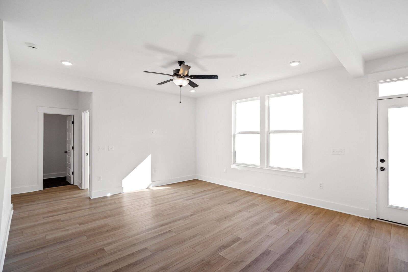 Bright living room with hardwood floors, ceiling fan, large windows, and French doors in Davidson Homes The Willow C, Gallatin, TN