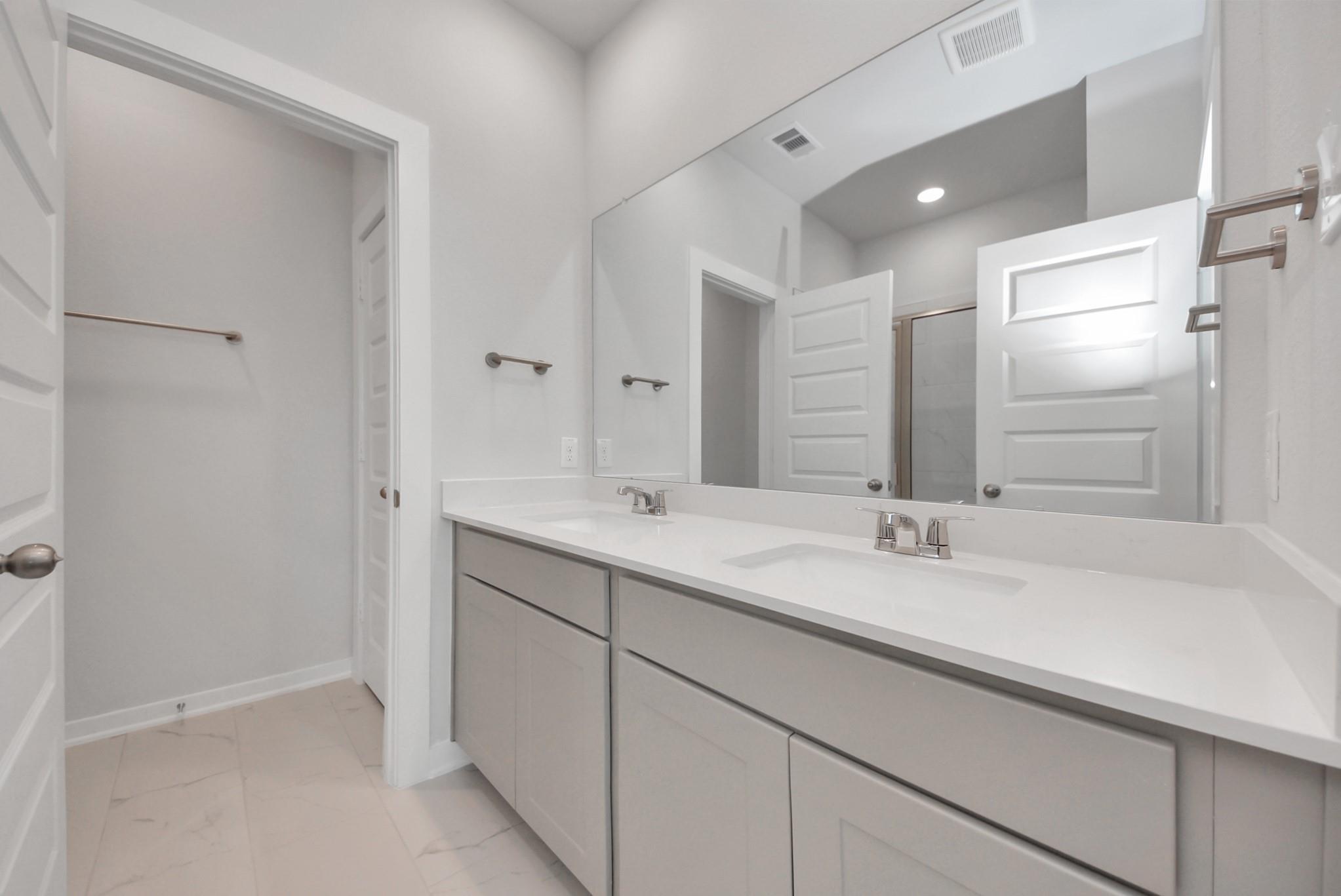Double vanity bathroom with quartz countertops and walk-in shower in The San Marcos E floor plan, Emberly, Beasley, TX